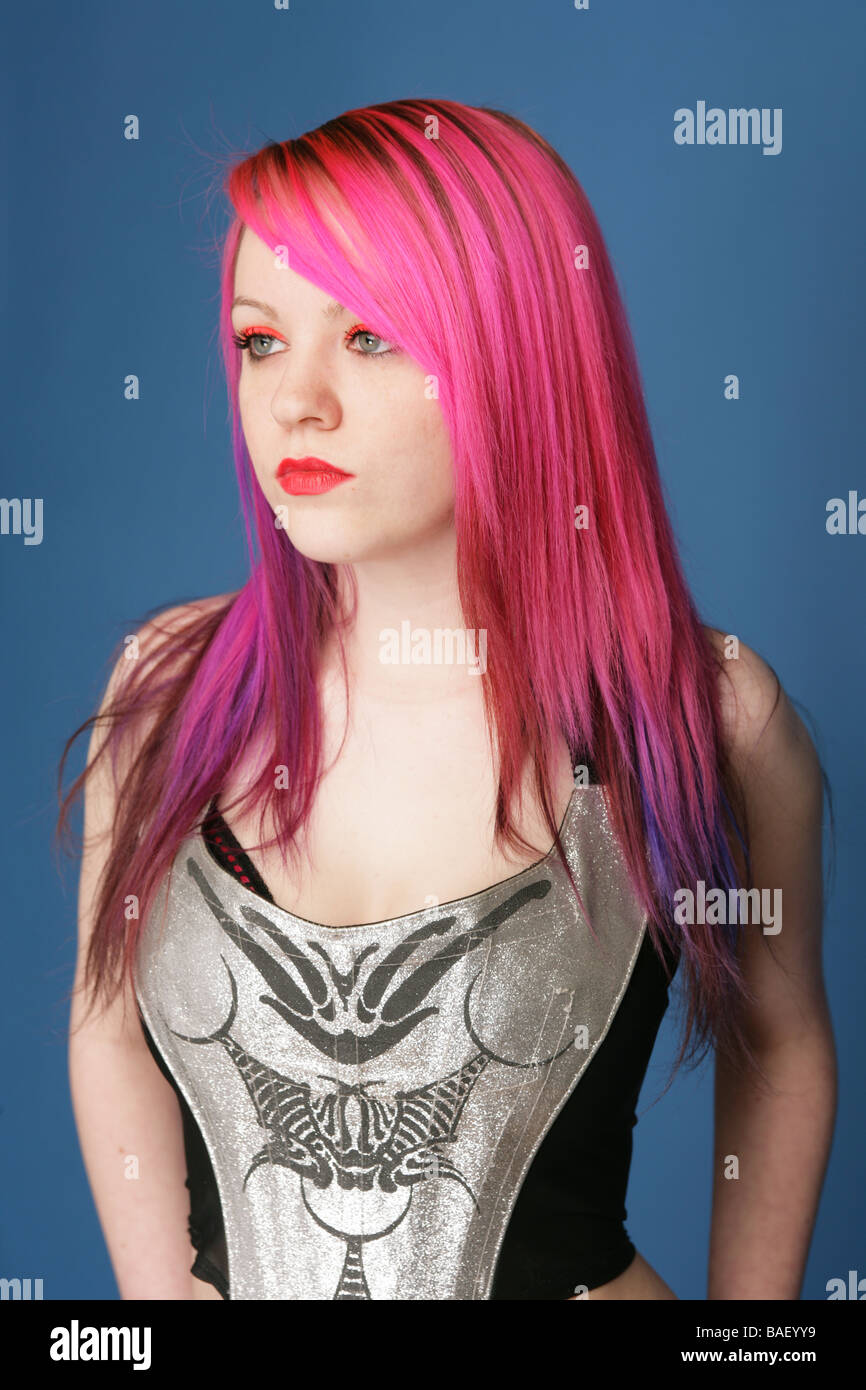 Portrait of a eighteen year old cyber goth with pale skin and red hair and lipstick wearing a silver top. Stock Photo