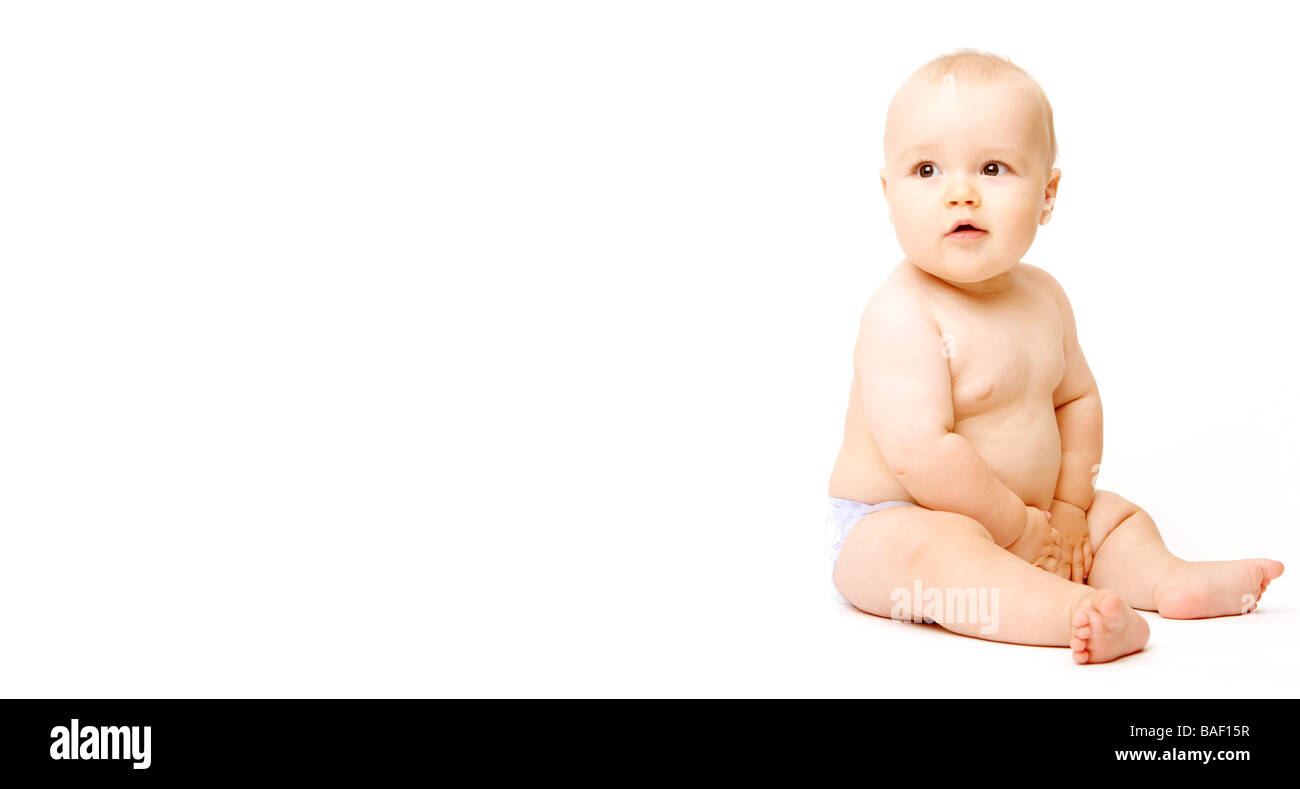 A baby sits on the right edge of a white background in his nappy Stock Photo