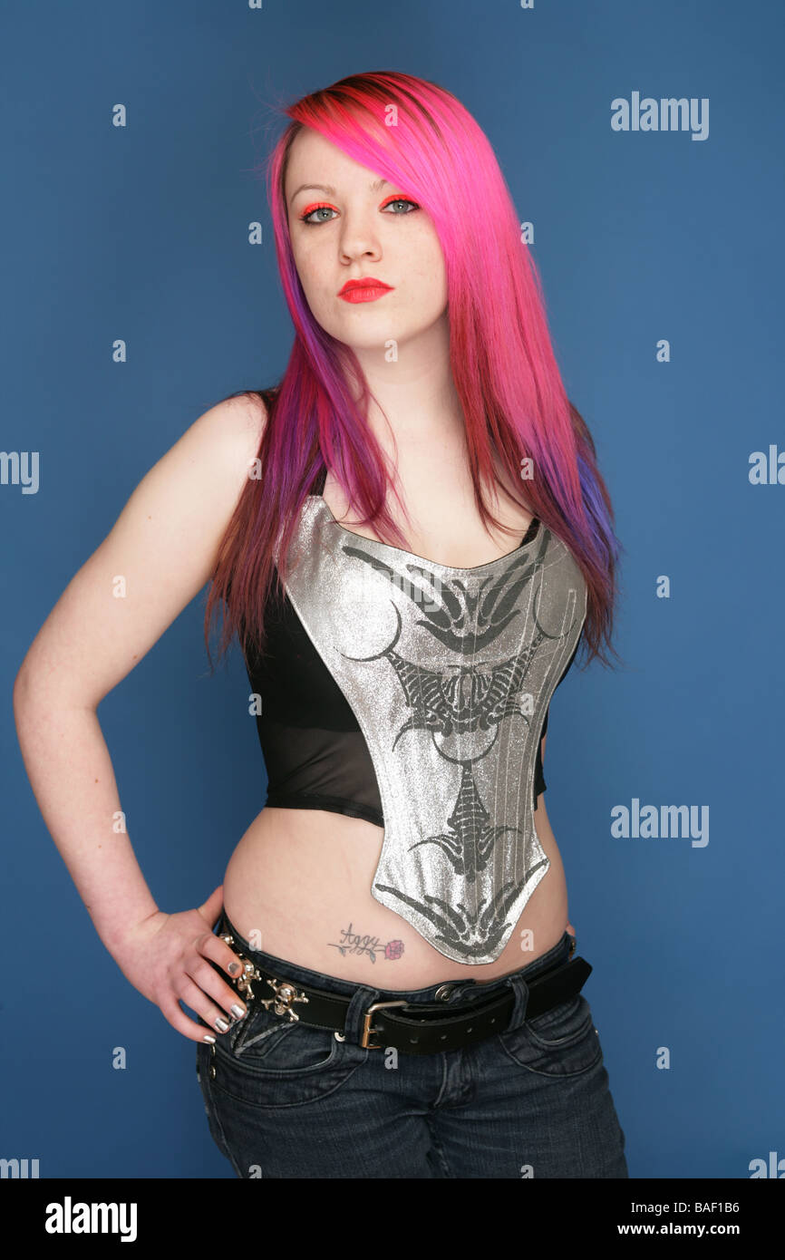 Young teen with bright pink hair red lips and pale skin standing with her hands on her hips Stock Photo