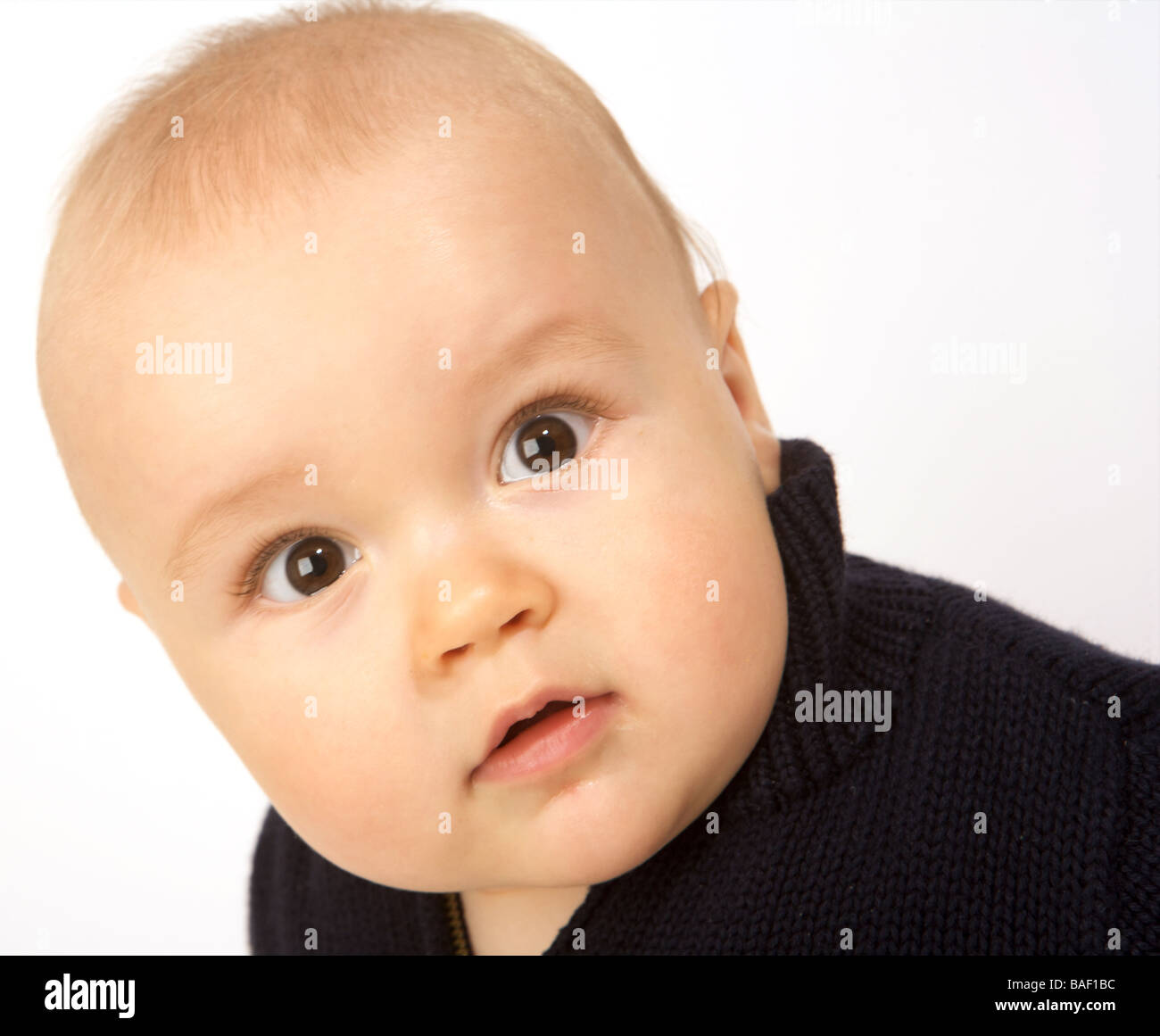 A baby looks startled against a white background Stock Photo