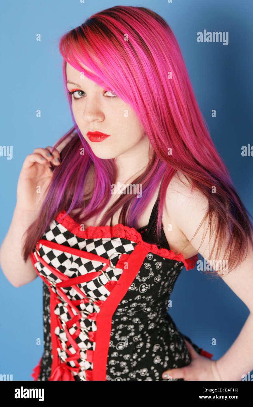 Portrait of a beautiful teen girl with long pink hair pale skin and red lips wearing a red and black dress. Stock Photo
