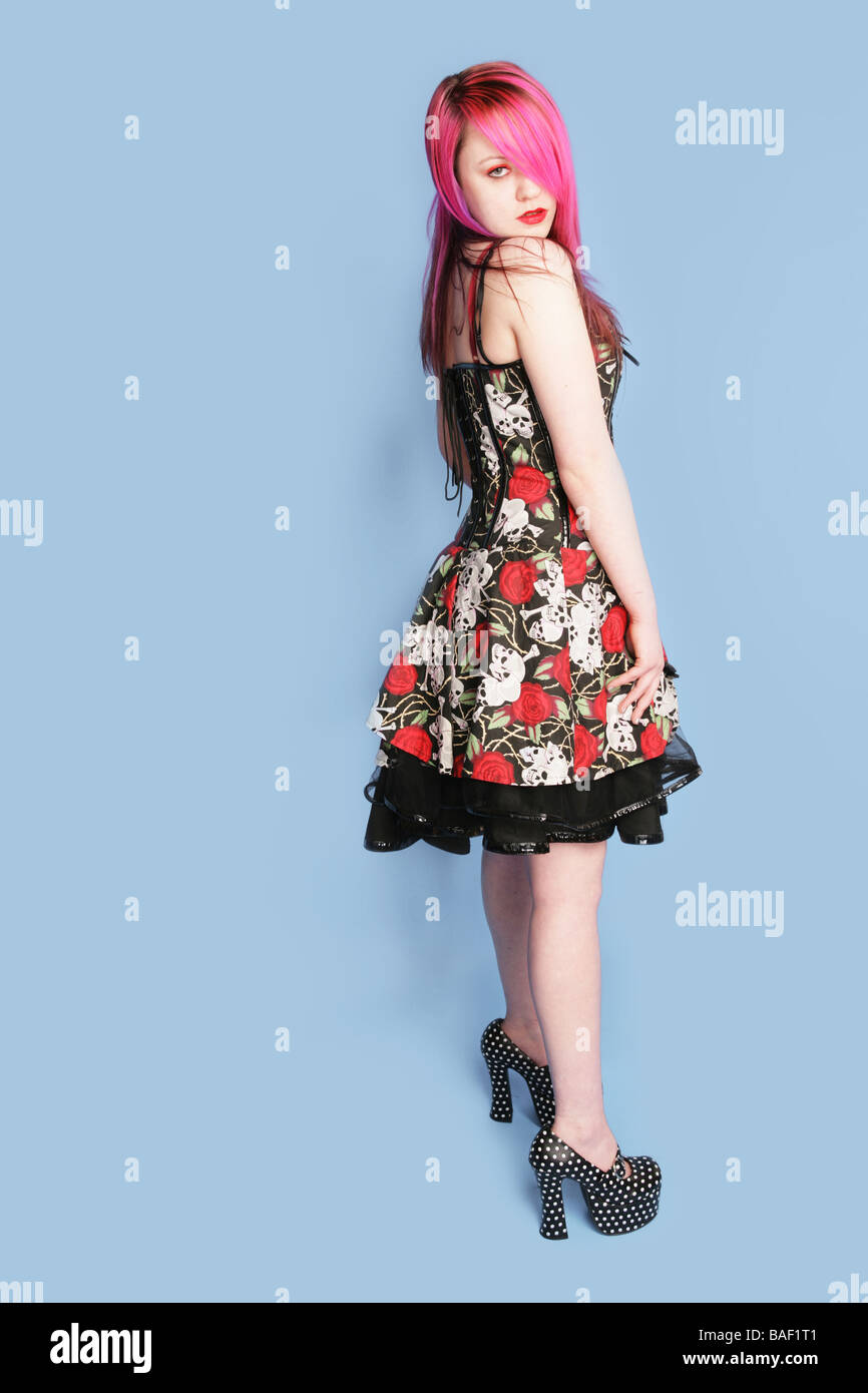 Full length portrait of a young teen goth girl wearing a dress and standing on a blue background Stock Photo