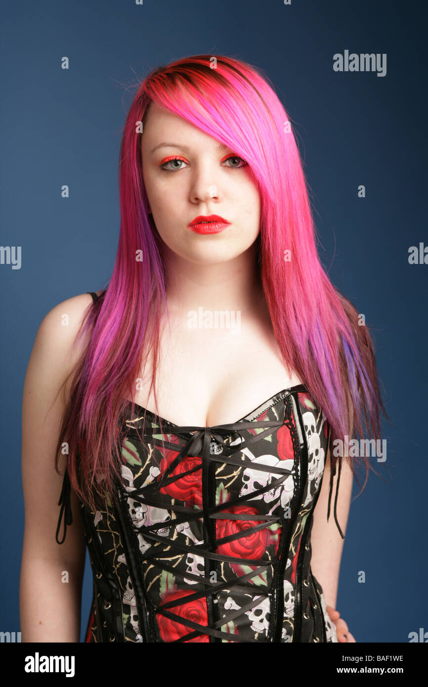 Portrait of a beautiful teen girl with long pink hair pale skin and red lips wearing a corset top. Stock Photo