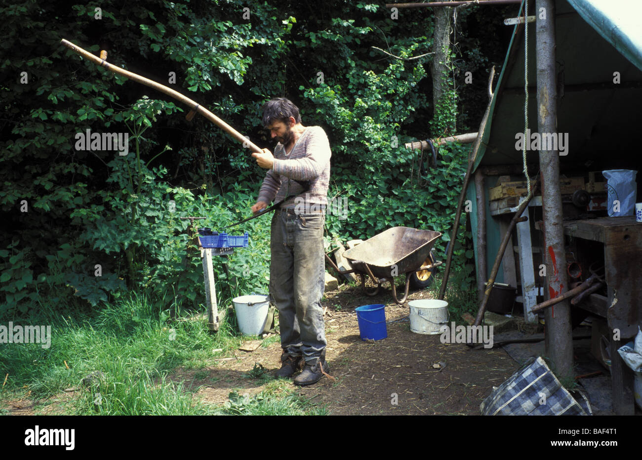 Simon Fairlie sharpening up a scythe during haymaking Tinker s Bubble Somerset Stock Photo