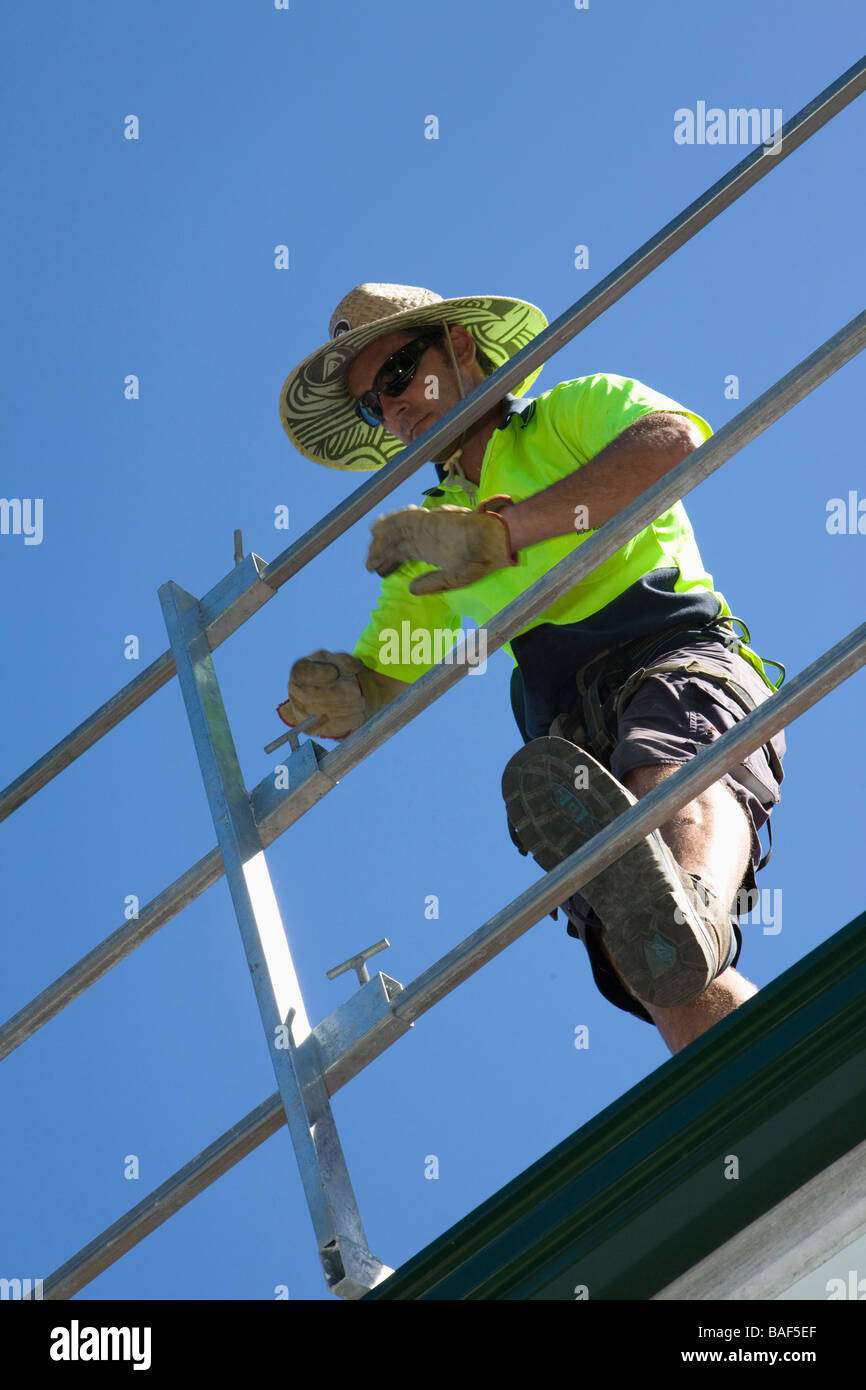 Man erecting safety rails around terra cotta tiled roof, Sydney, New South Wales, Australia Stock Photo