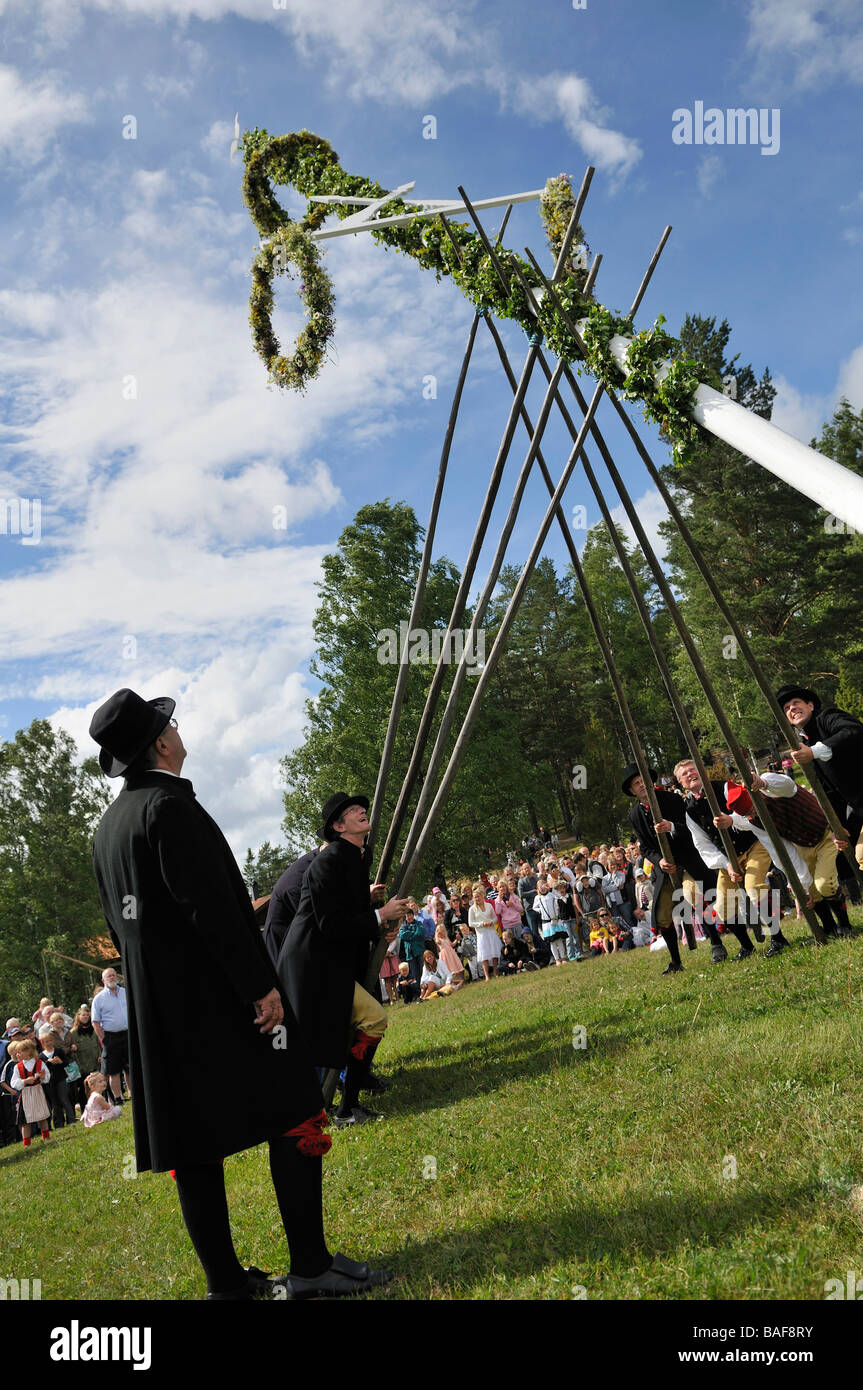 Men with costumes putting up Midsummer Pole at Midsummer celebration in Doessberget Sweden June 2008 Stock Photo
