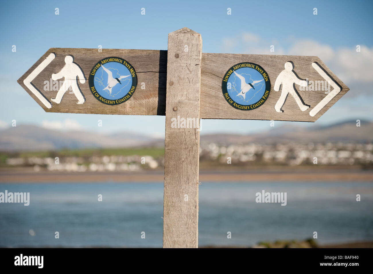 A wooden fingerpost on the coastal footpath around the coastline of the isle of Anglesey Gwynedd north wales spring afternoon Stock Photo