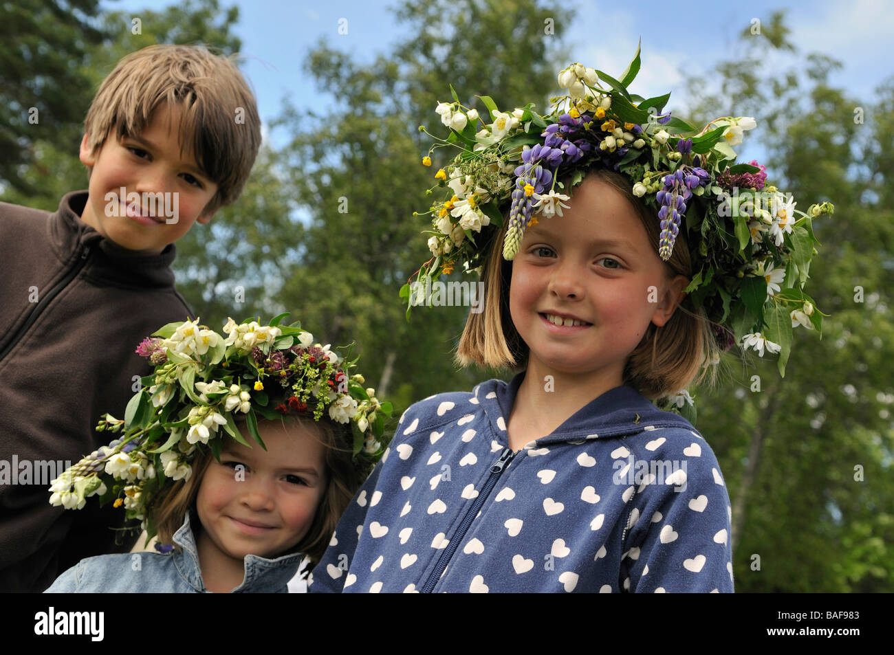 Smiling girls with floral wreath and boy at Midsummer celebration in Doessberget Sweden June 2008 Stock Photo