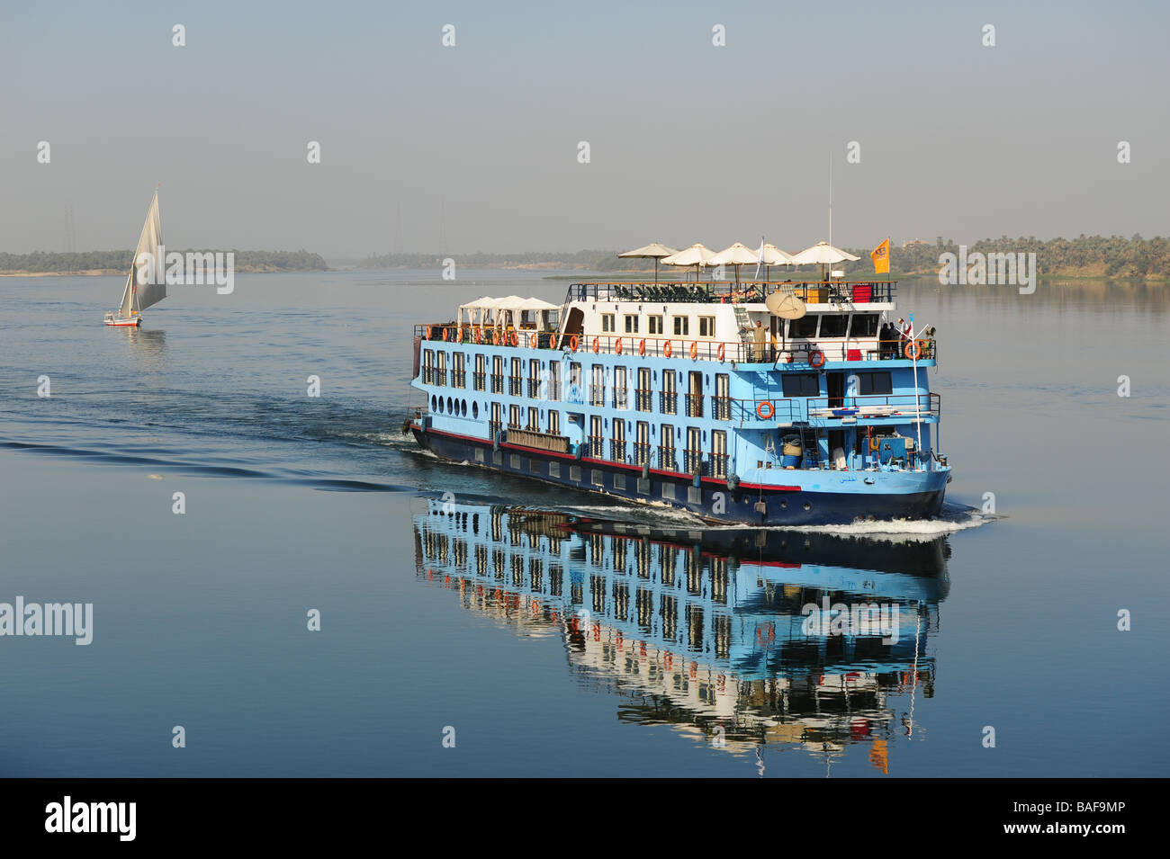 Africa Egypt A Nile River cruise boat heads North in the calm waters with a felucca sailboat behind it Stock Photo