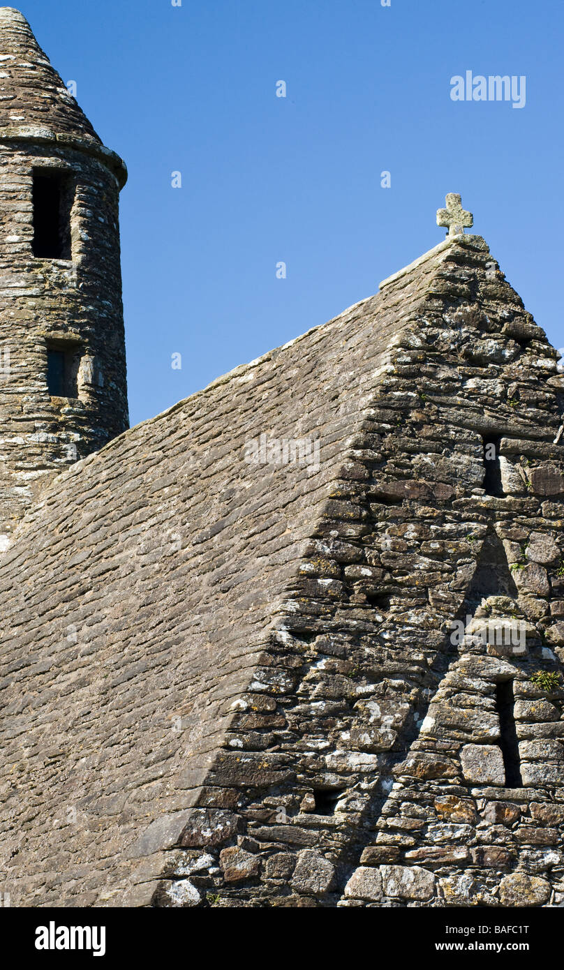 Simplicity in Stone Vertical A detailed view of the tower and stone roof of the St Kevin's Chapel.  A rock cross adorns the roof Stock Photo