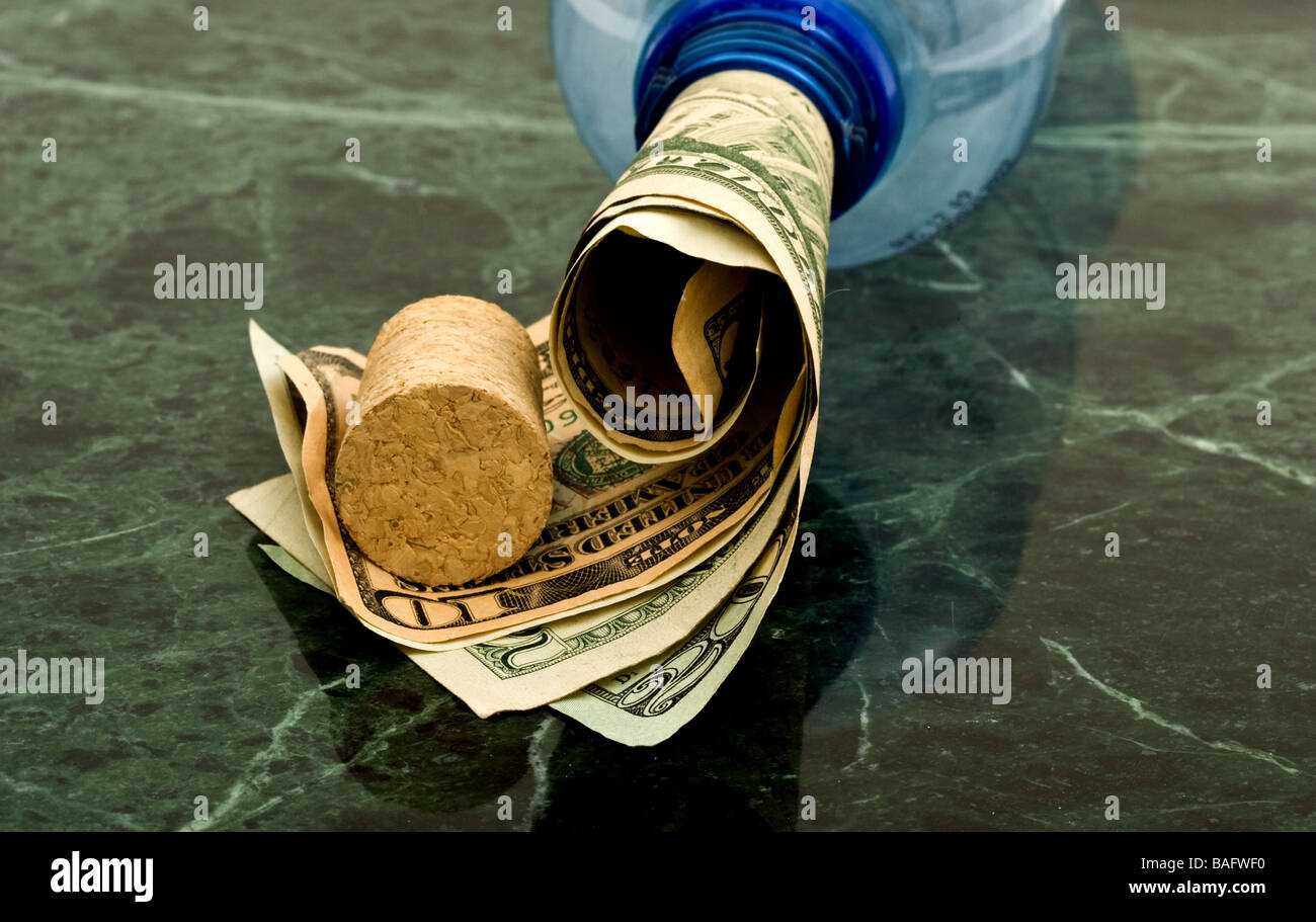 Bottle with a roll of money coming out from the top next to a cork Stock Photo