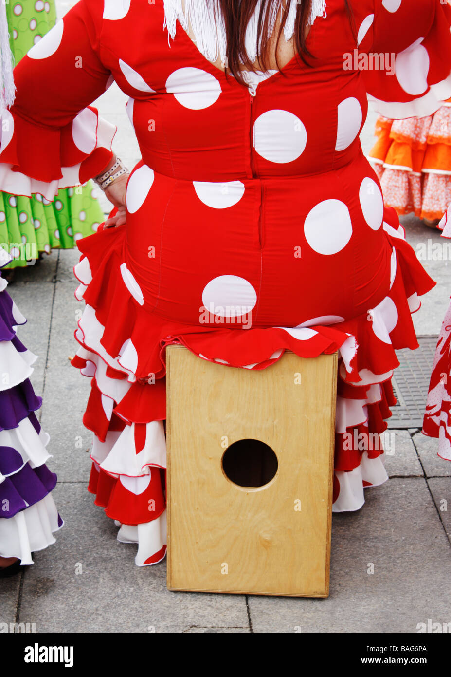Flamenco dancer in polka dot dress sitting on Cajon (percussion