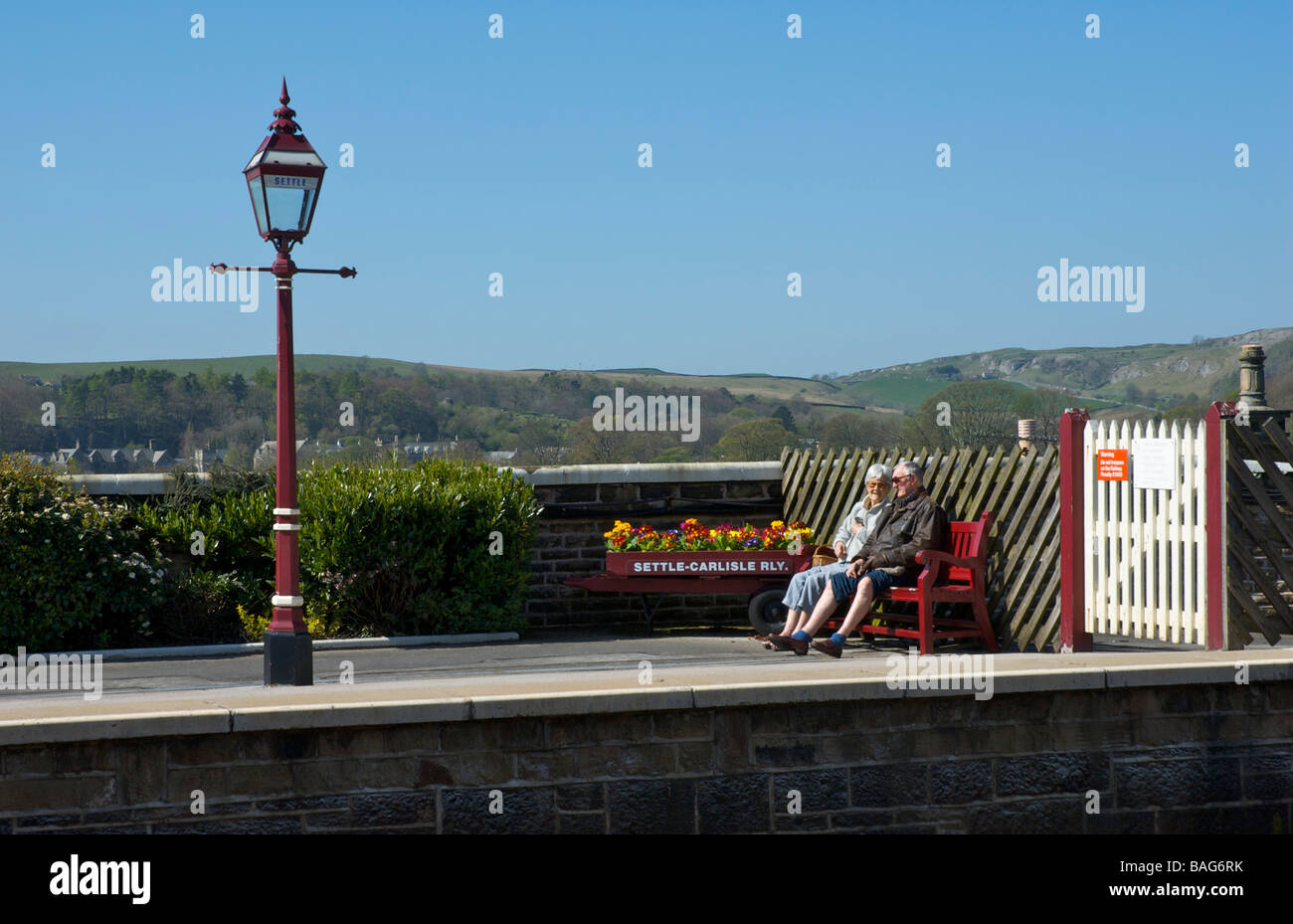 Elderly couple sitting on a bench at Settle railway station, North Yorkshire, England UK Stock Photo