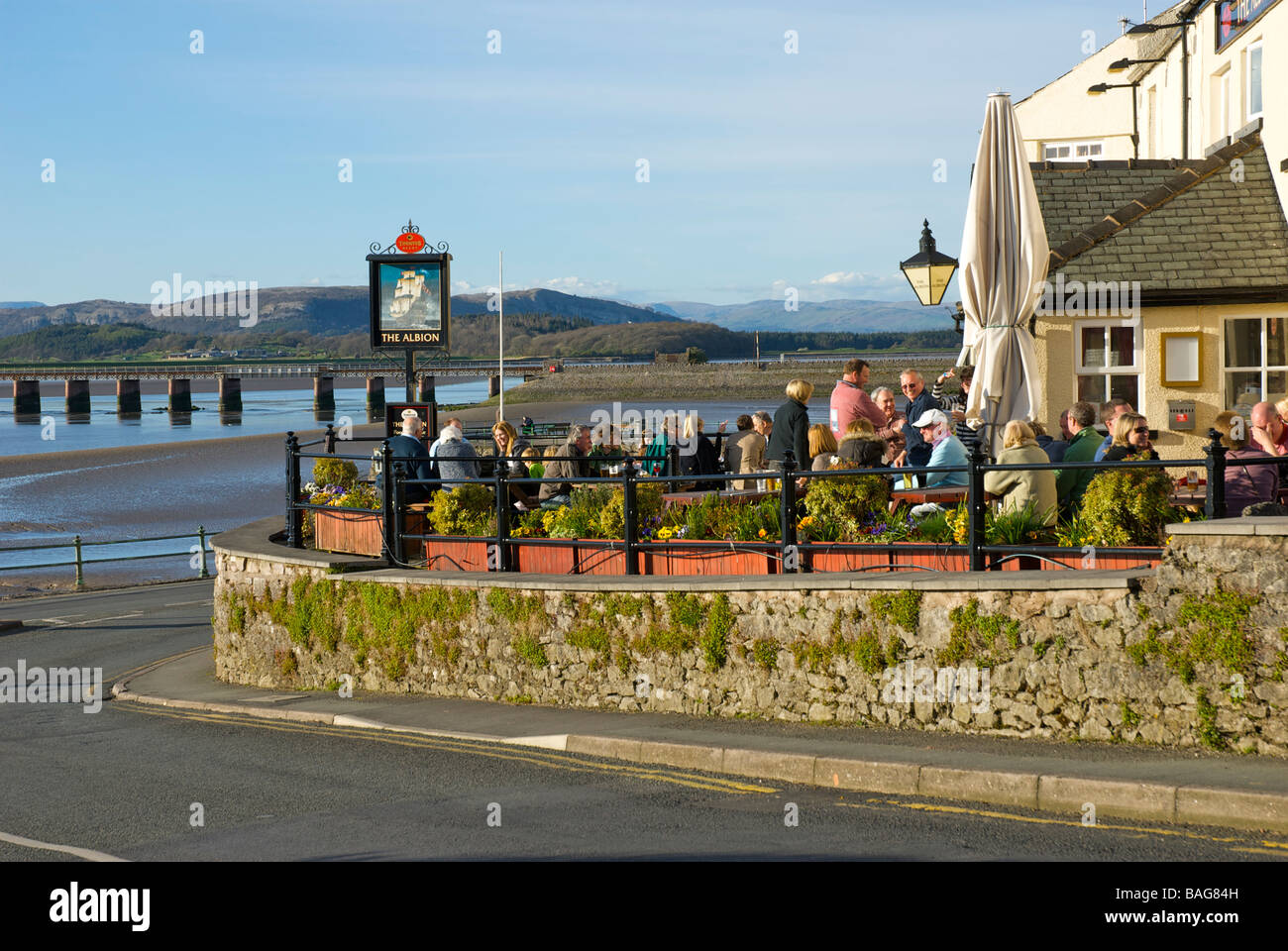 People enjoying a drink on the terrace of the Albion pub, overlooking the Kent Estuary, in the village of Arnside, Cumbria, UK Stock Photo