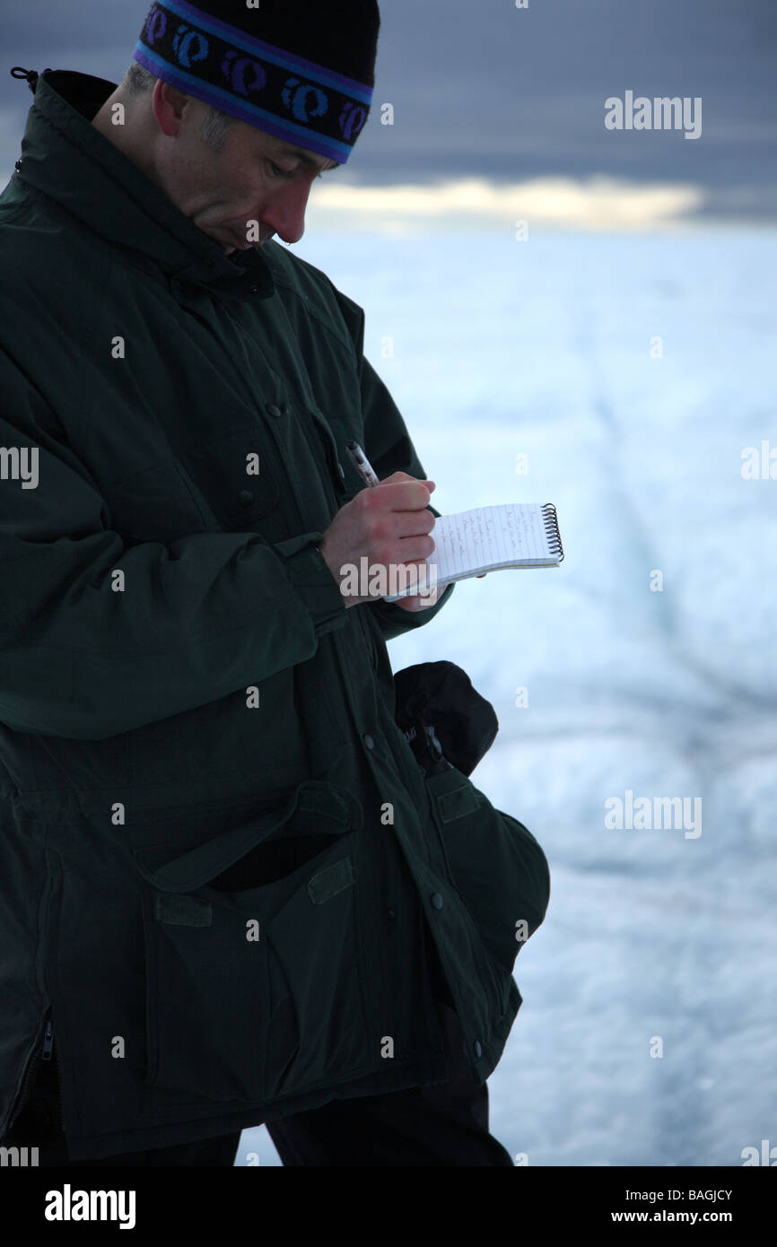 Executive Editor of the National Geographic Society Magazine, Tim Appenzeller writing notes on the ice in Greenland Stock Photo