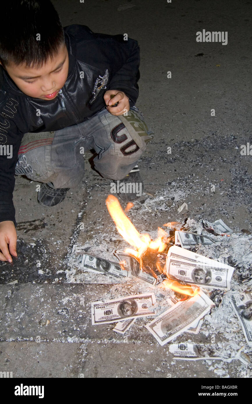 Vietnamese child burning photocopied U S dollars for good luck and prosperity during Tet festivities in Hanoi Vietnam Stock Photo