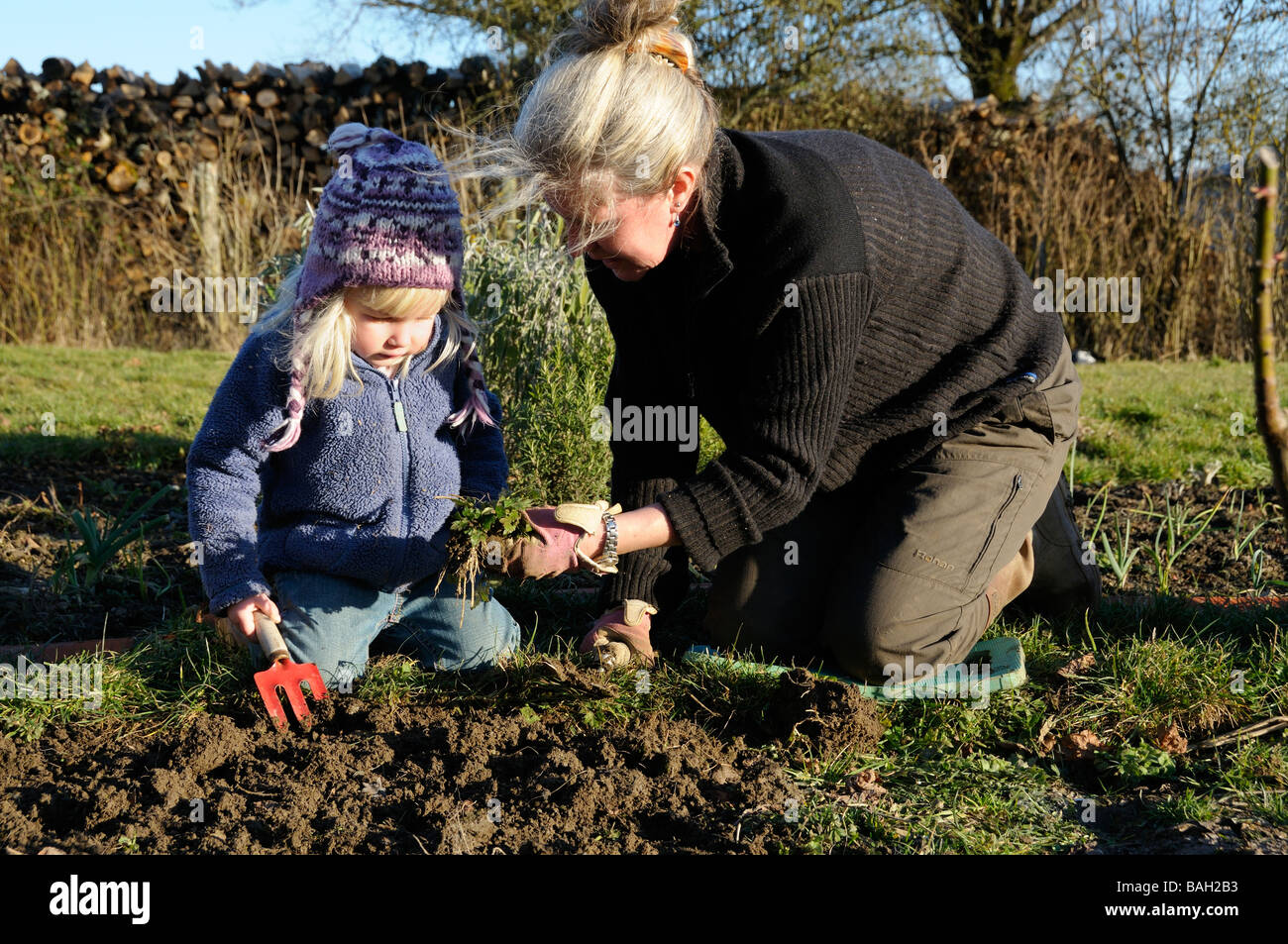 A 3 year old girl helping her mother weeding the garden Stock Photo - Alamy