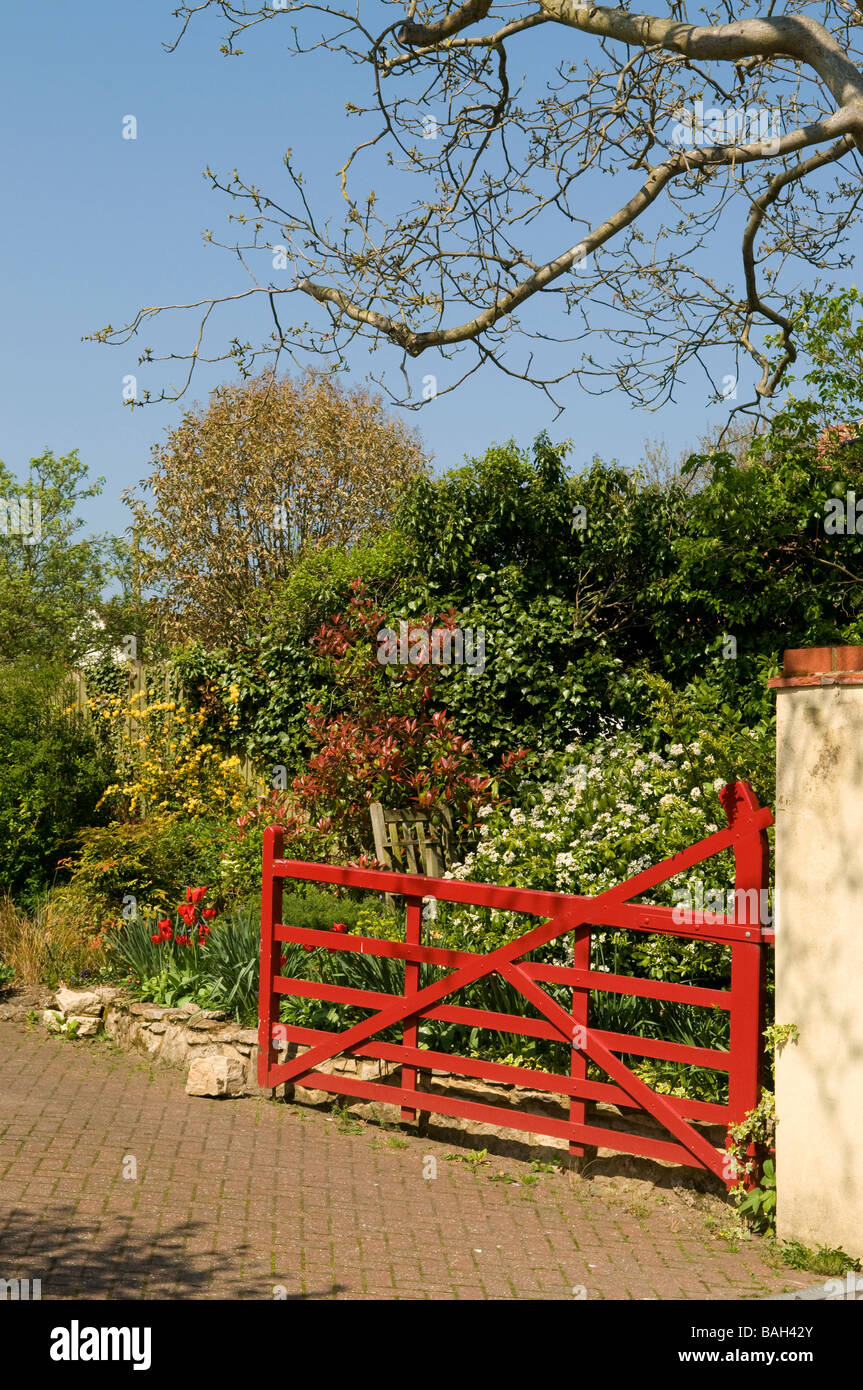 Red garden gate in blossoming garden Stock Photo