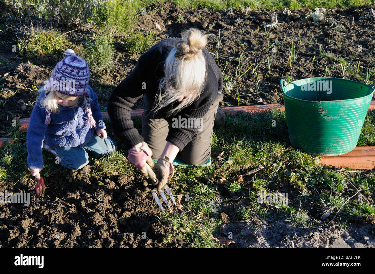 A 3 year old girl helping her mother weeding the garden Stock Photo - Alamy