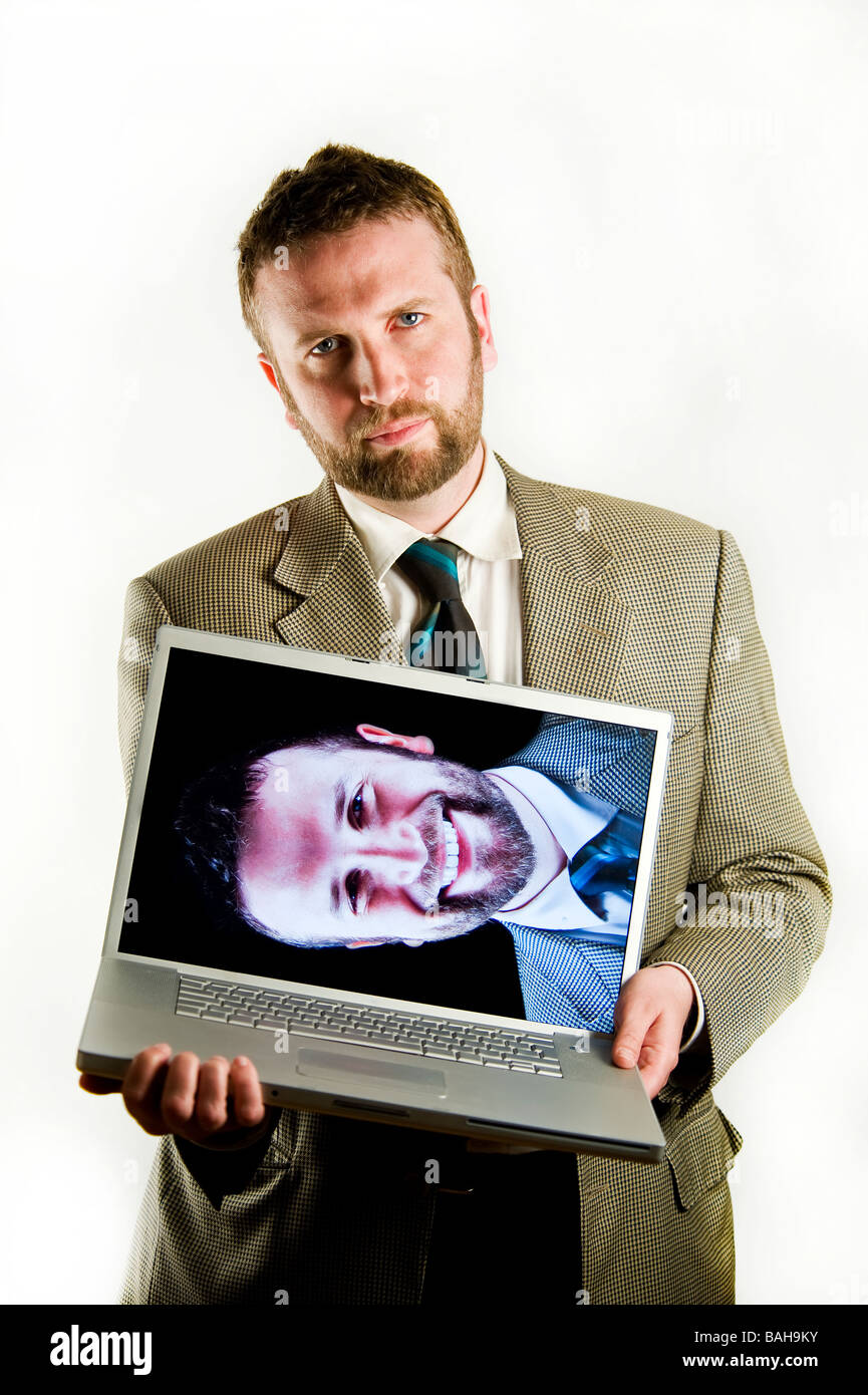 A well dressed, suited man holding a laptop in front of his body. The ...