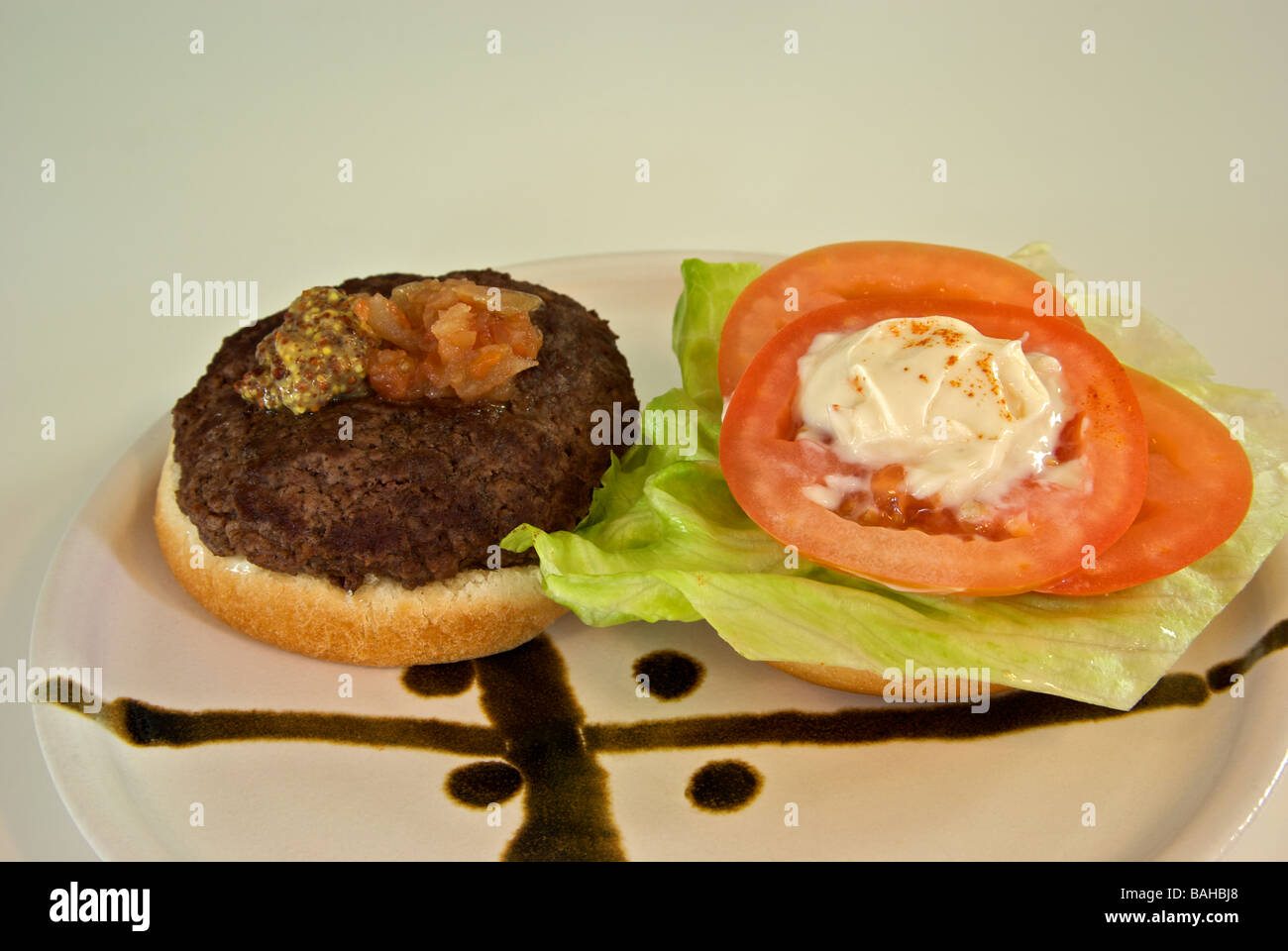 Deluxe hamburger lettuce tomato relish mustard on a bun Stock Photo