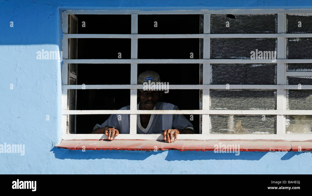 Sad looking man gazing through barred window, Havana, Cuba Stock Photo