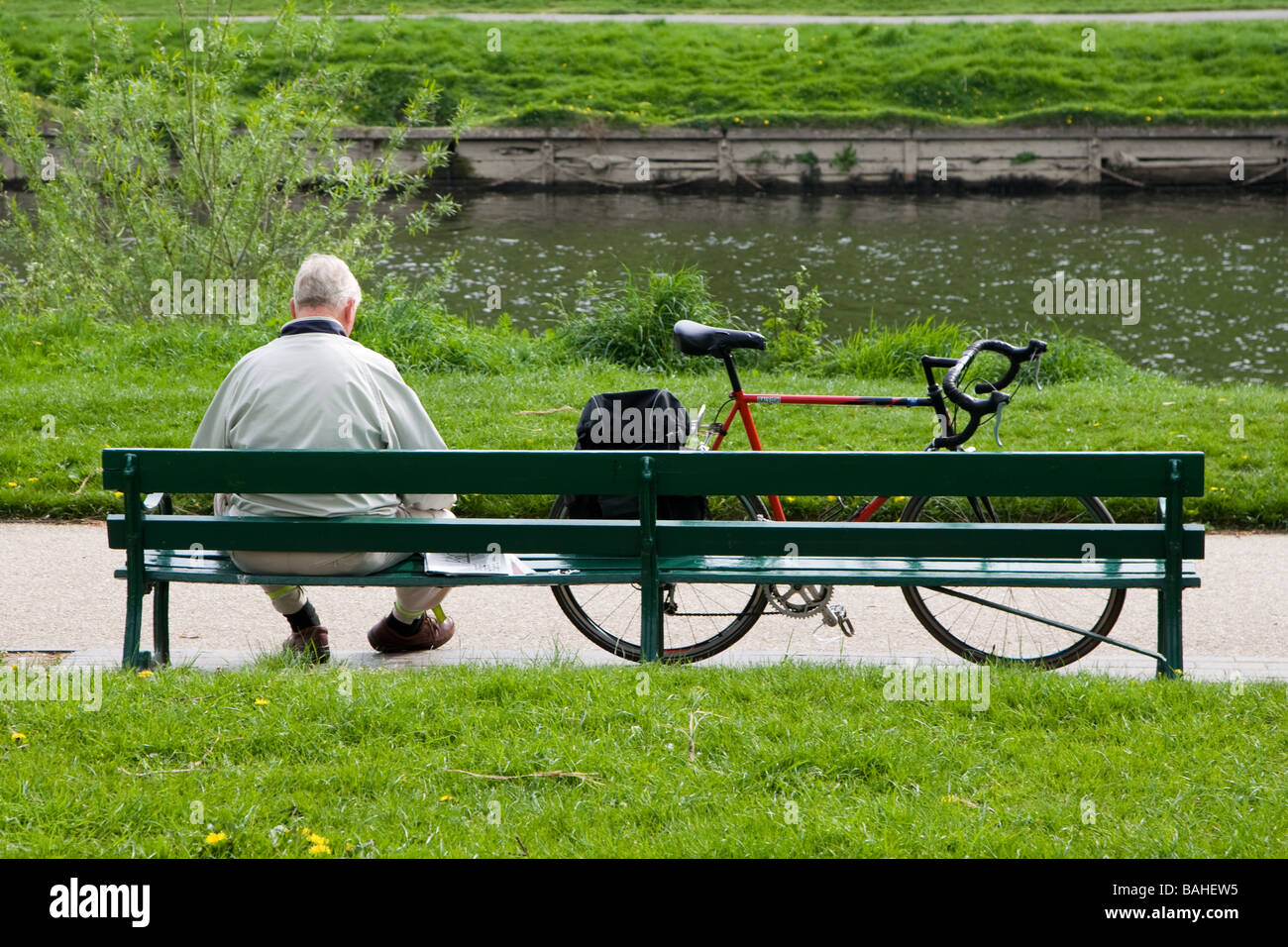 Elderly Cyclist relaxing on a riverside bench Stock Photo - Alamy