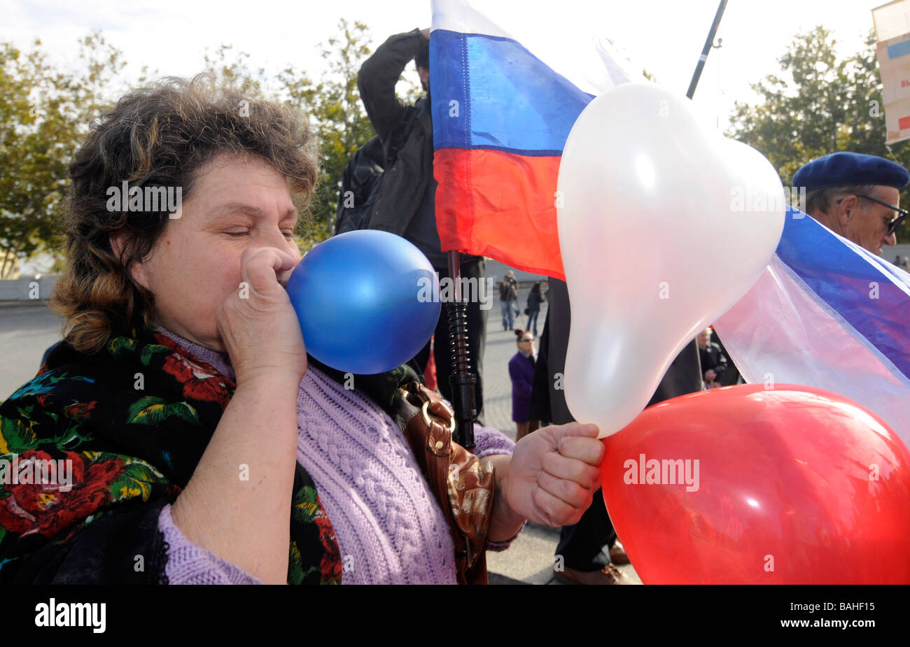 A Russian woman blowing balloons with the colours of Russia's national flag during a pro-Kremlin demonstration. Stock Photo