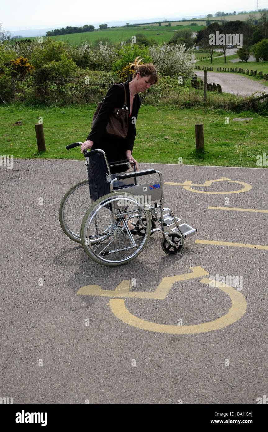 Disabled drivers parking place and sign woman preparing wheelchair for use Stock Photo