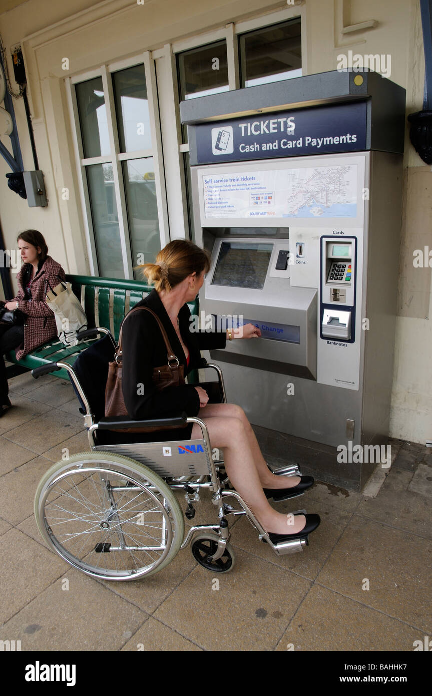 wheelchair user woman purchasing a railway ticket from automated ...