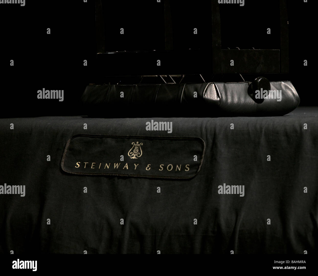 A closeup of covered Steinway Piano on stage with upturned stool Stock Photo