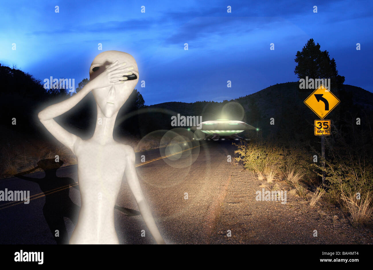 Landed UFO sighting with extraterrestrial in car headlights on rural back road Stock Photo