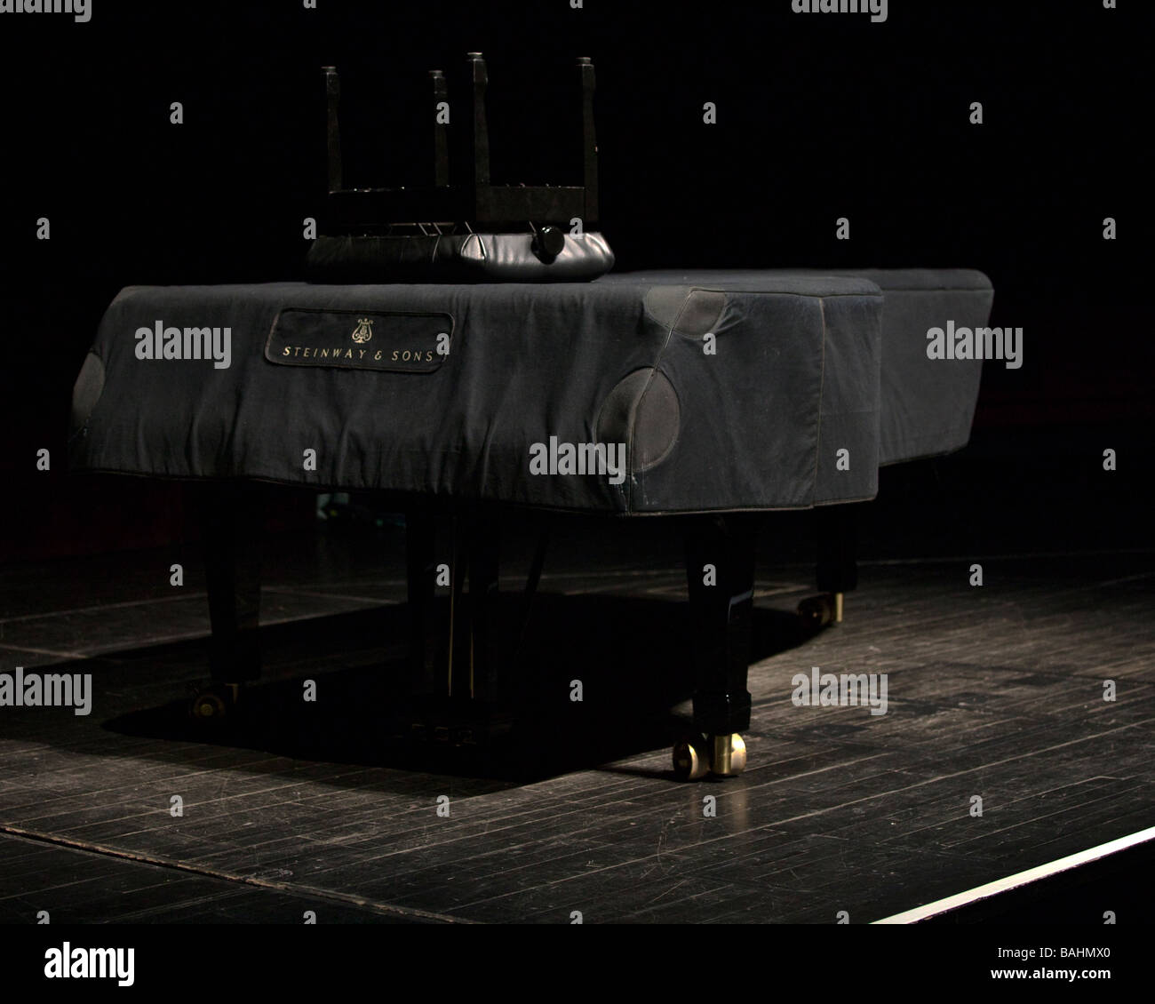 A covered Steinway Piano on stage with upturned stool Stock Photo