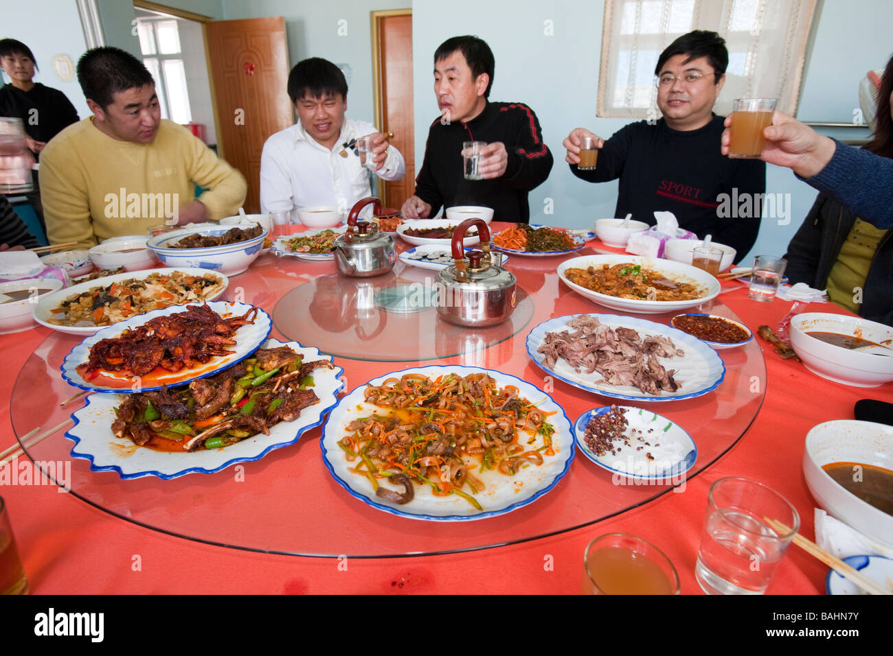 Chinese people sit down for a meal in a restaurant which includes several dishes of dog meat Stock Photo