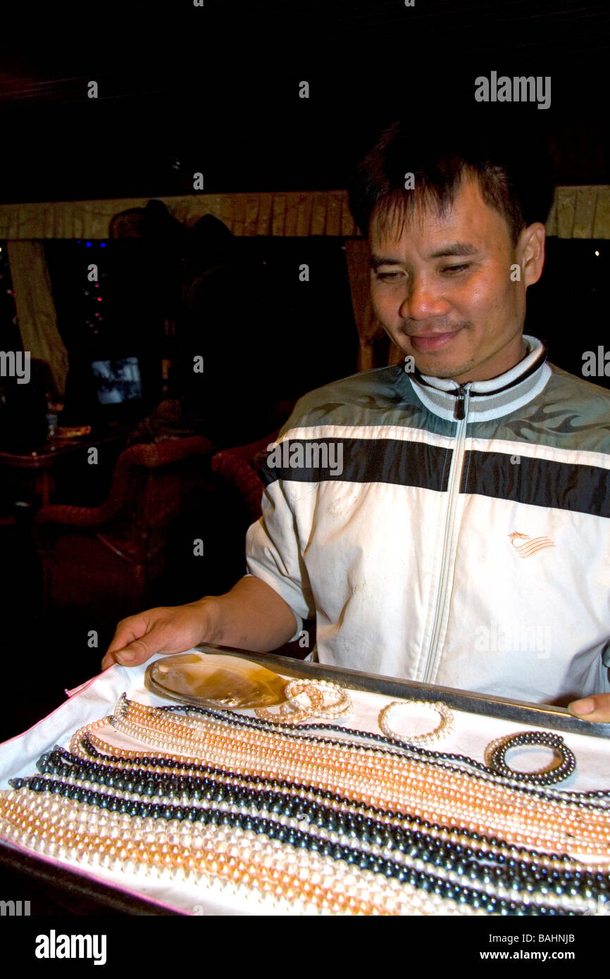 Vietnamese man selling pearl jewelry to tourists on a boat in Ha Long Bay Vietnam Stock Photo