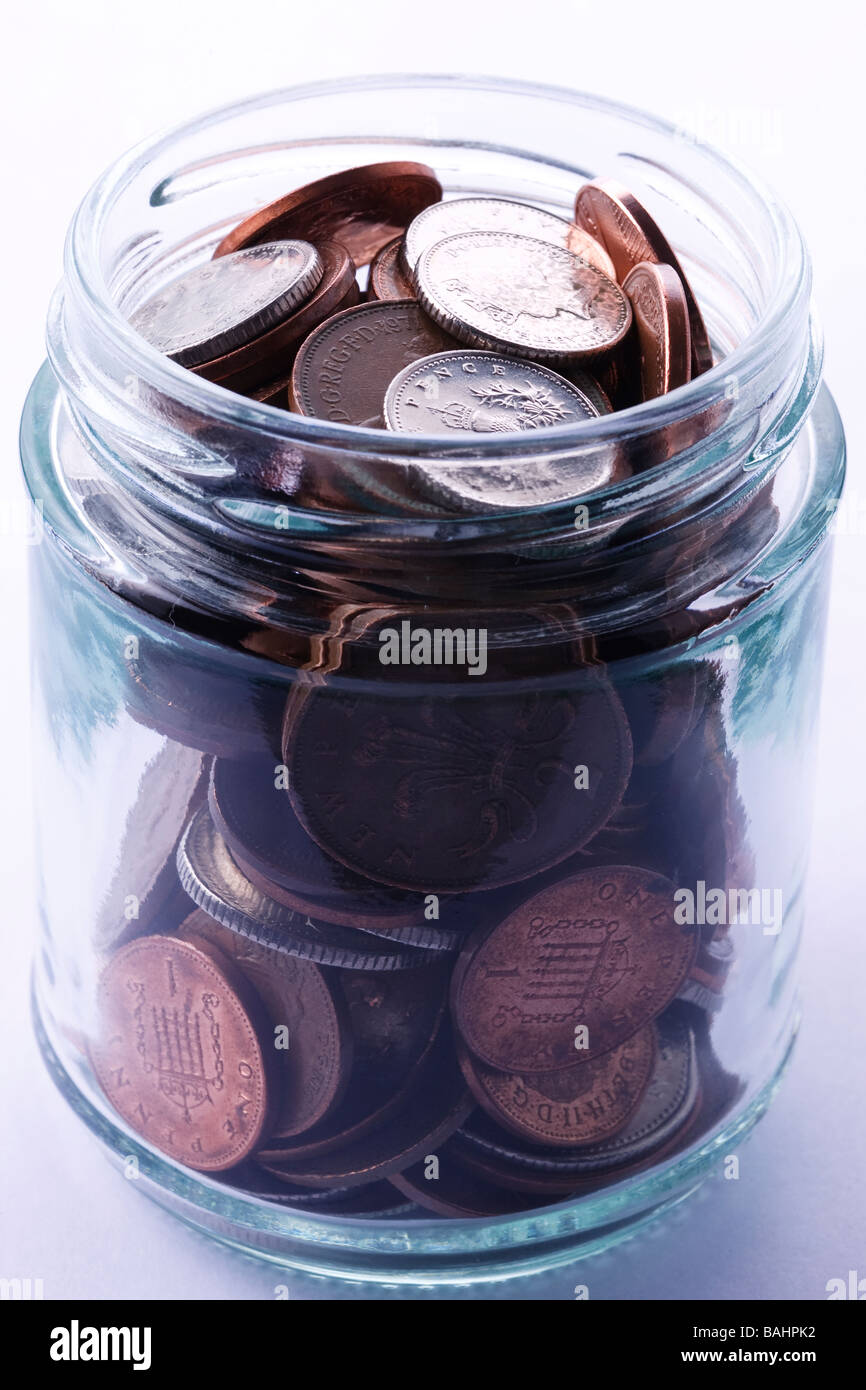 Glass jar containing small domination coins Stock Photo