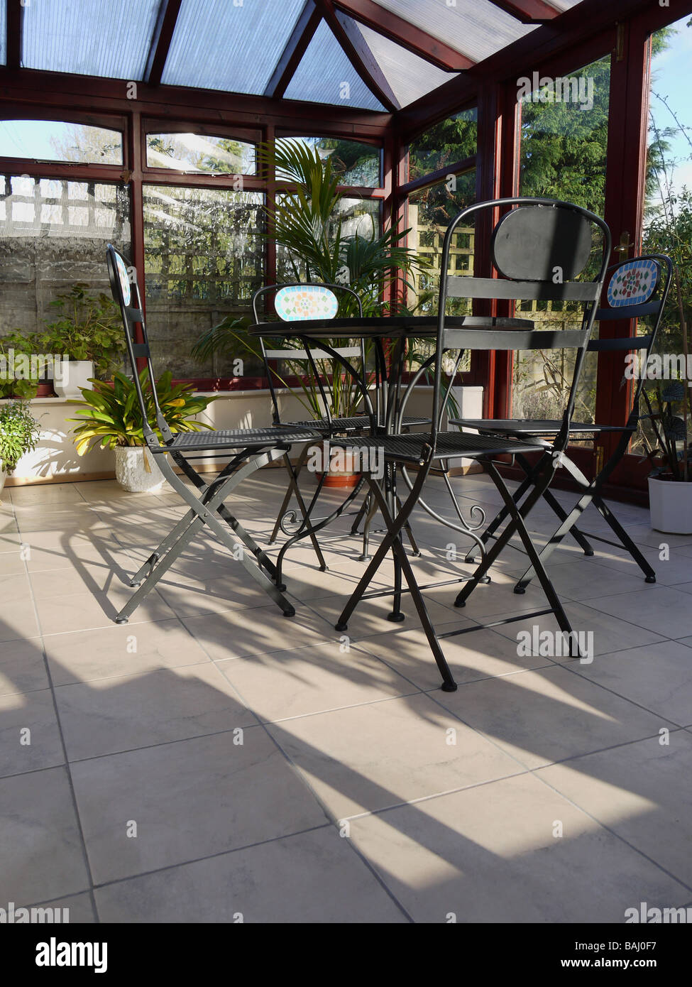 A conservatory with tables chairs plants in room in house next to