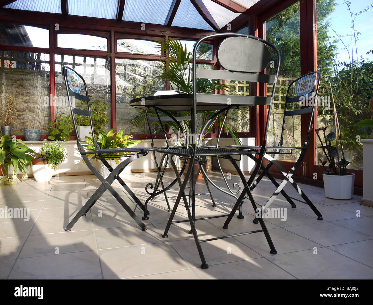 A conservatory with tables chairs plants in room in house next to