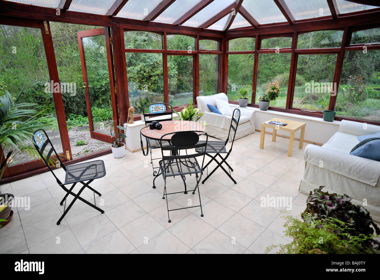 conservatory tables chairs plants room in house next to garden Stock