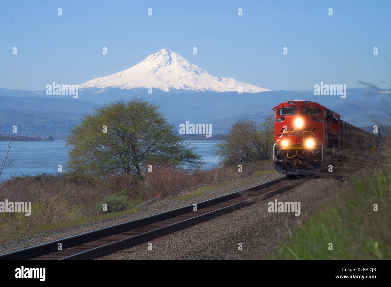 A BNSF Train passes thru the Columbia River Basin with Mount Hood Looming. Stock Photo