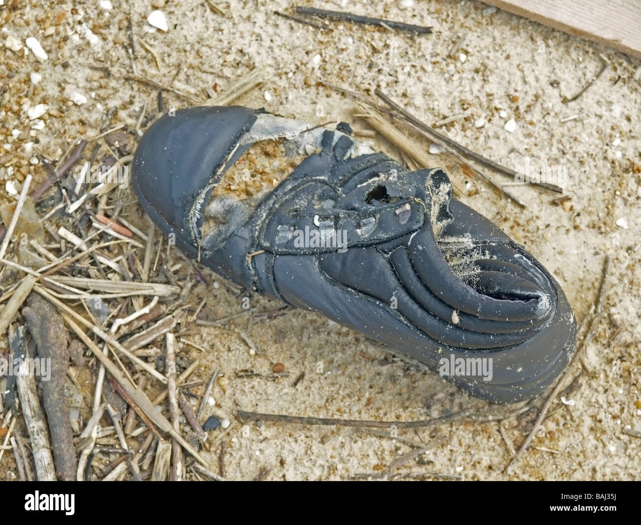 washed up kaputt shoe with sand at the coast of Atlantic Ocean France Stock Photo