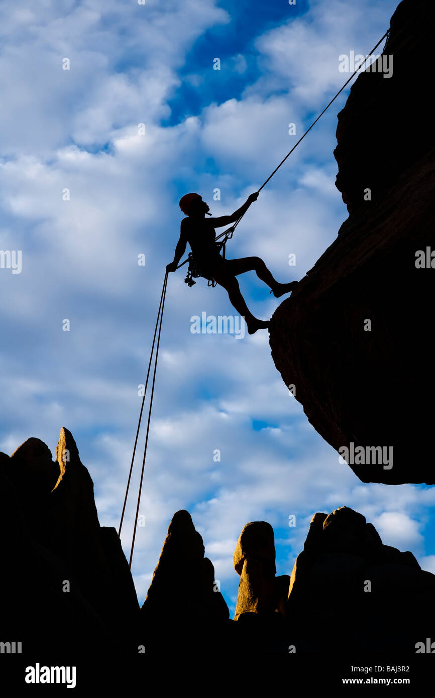 A climber rappelling from the summit of a rock spire after a successful