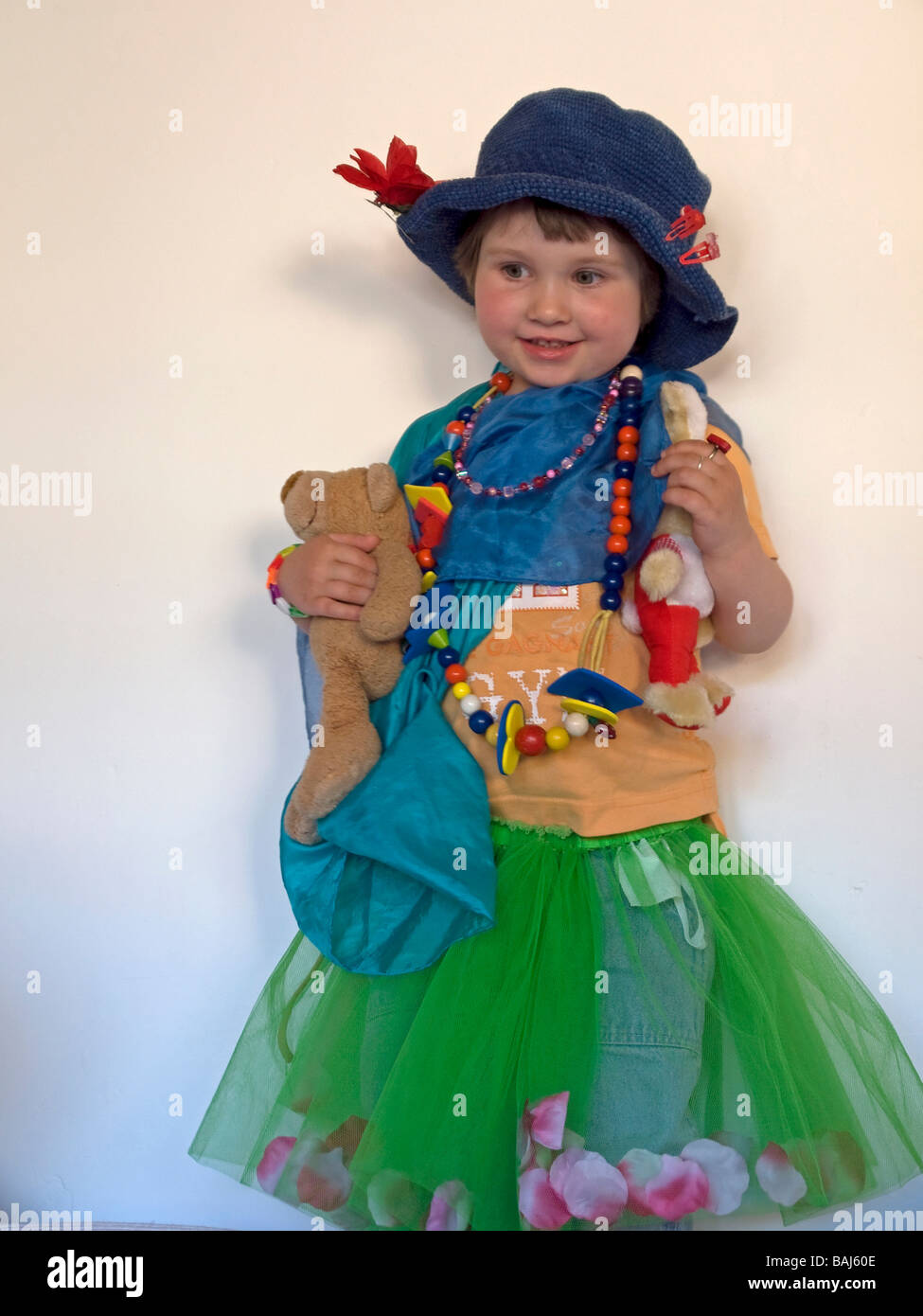 little girl 3 years old masquerading disguising itself as princess playing with teddy bear Stock Photo