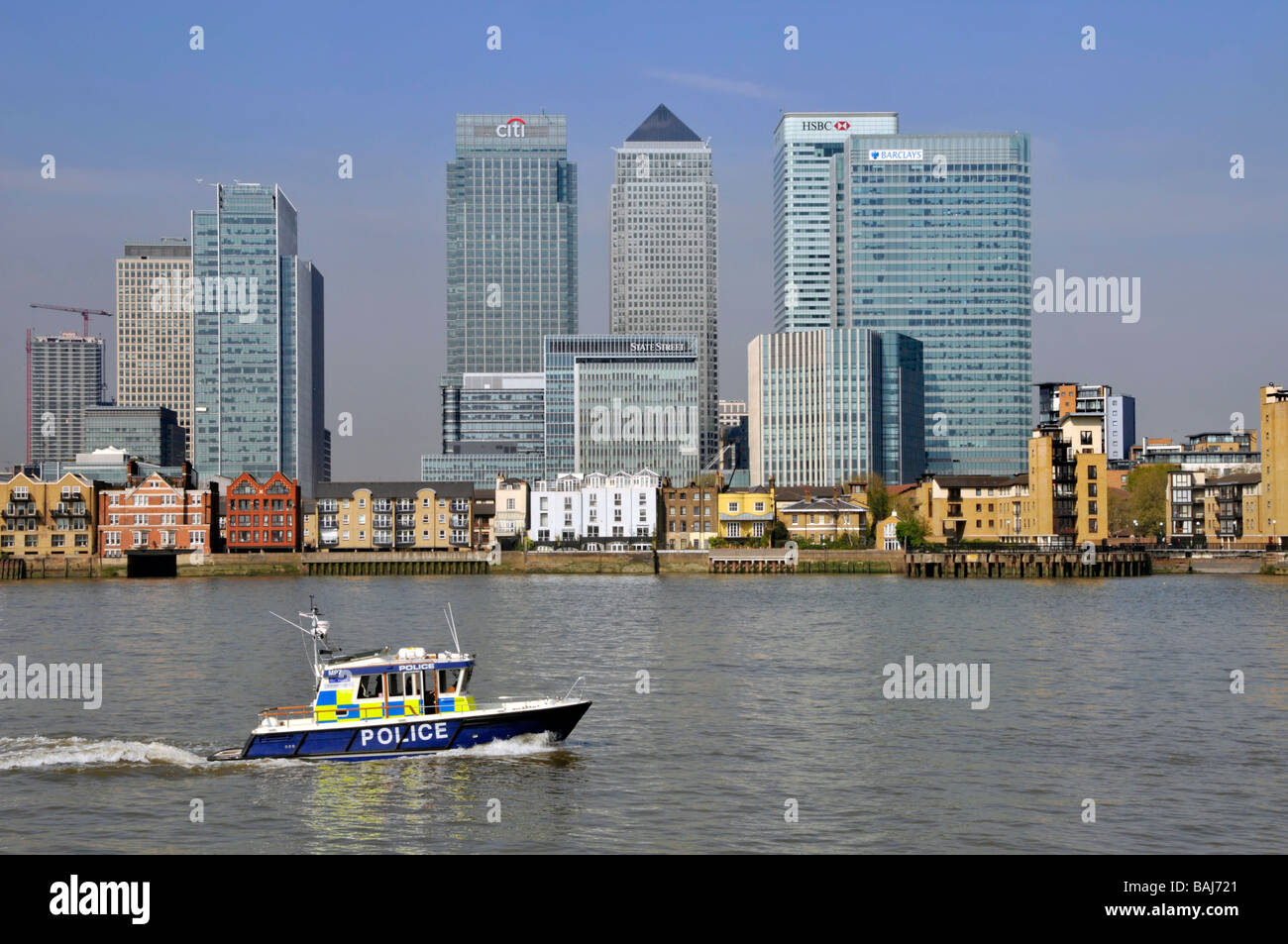 Landmark riverside business & banks offices in Canary Wharf urban development in East London Docklands beside River Thames a Met police patrol boat UK Stock Photo