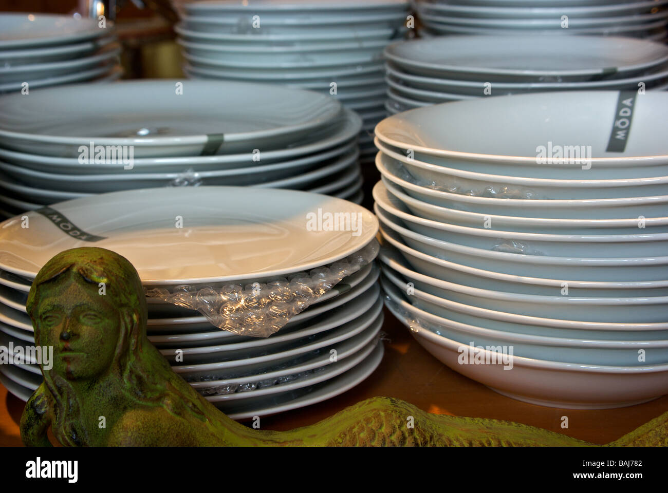 Stacks of round dinner porcelain plates and bowls on display for sale