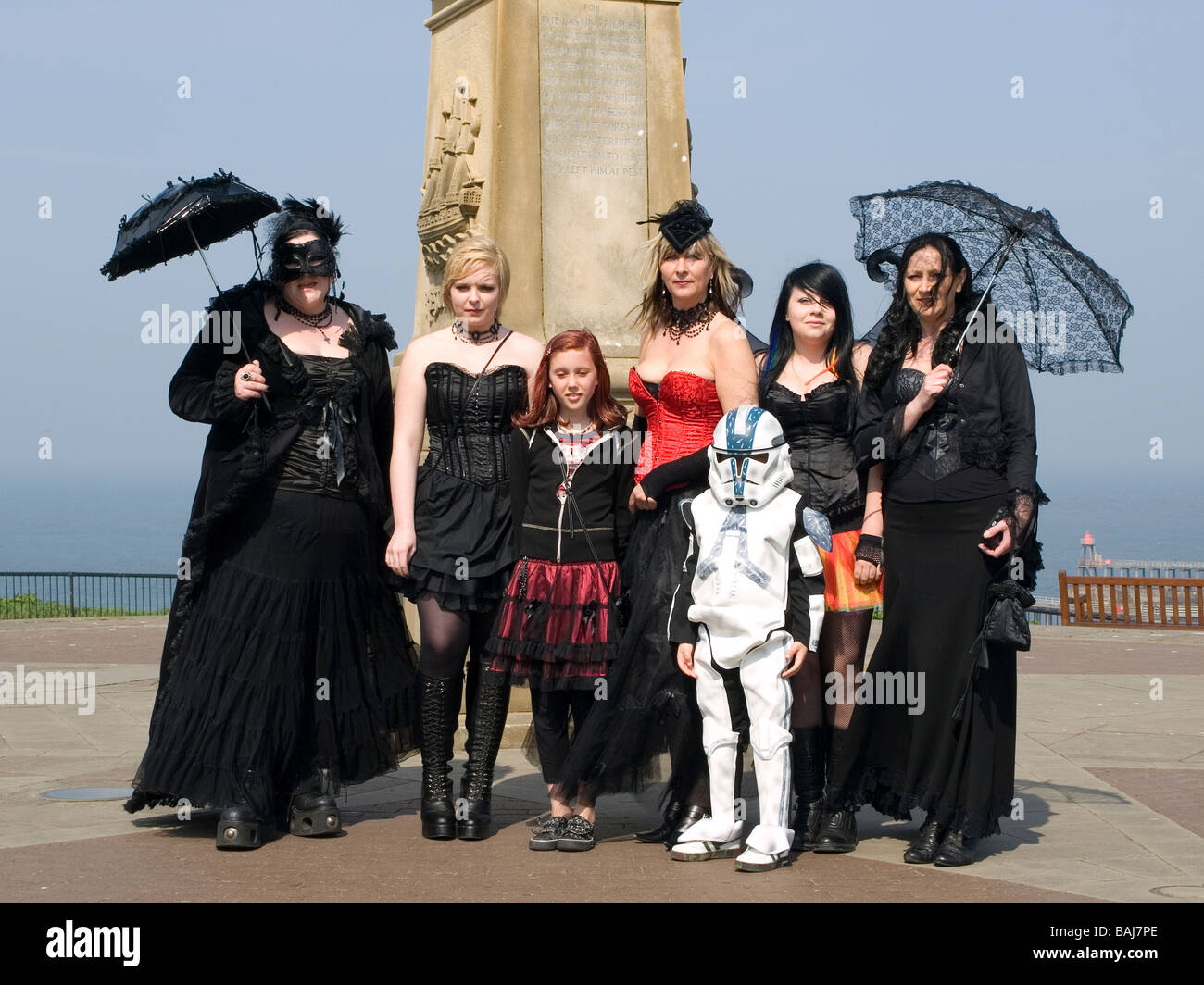 A group of women and children dressed as Goths pose in front of James Cooks statue at the biannual Goth festival in Whitby Stock Photo