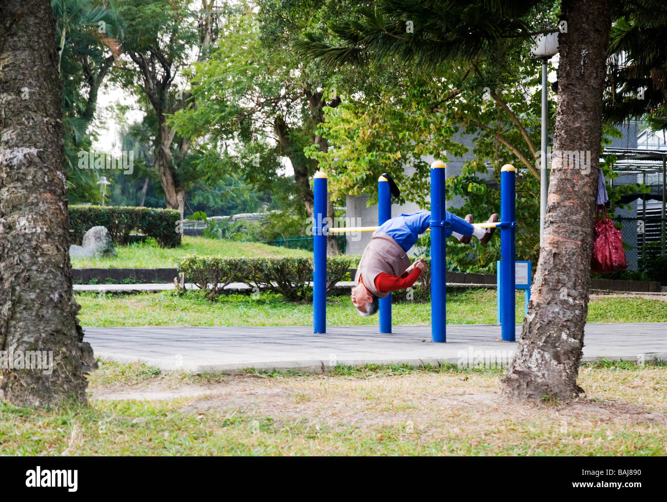 old man exercising by stretching in park in early morning in Taipei, Taiwan Stock Photo