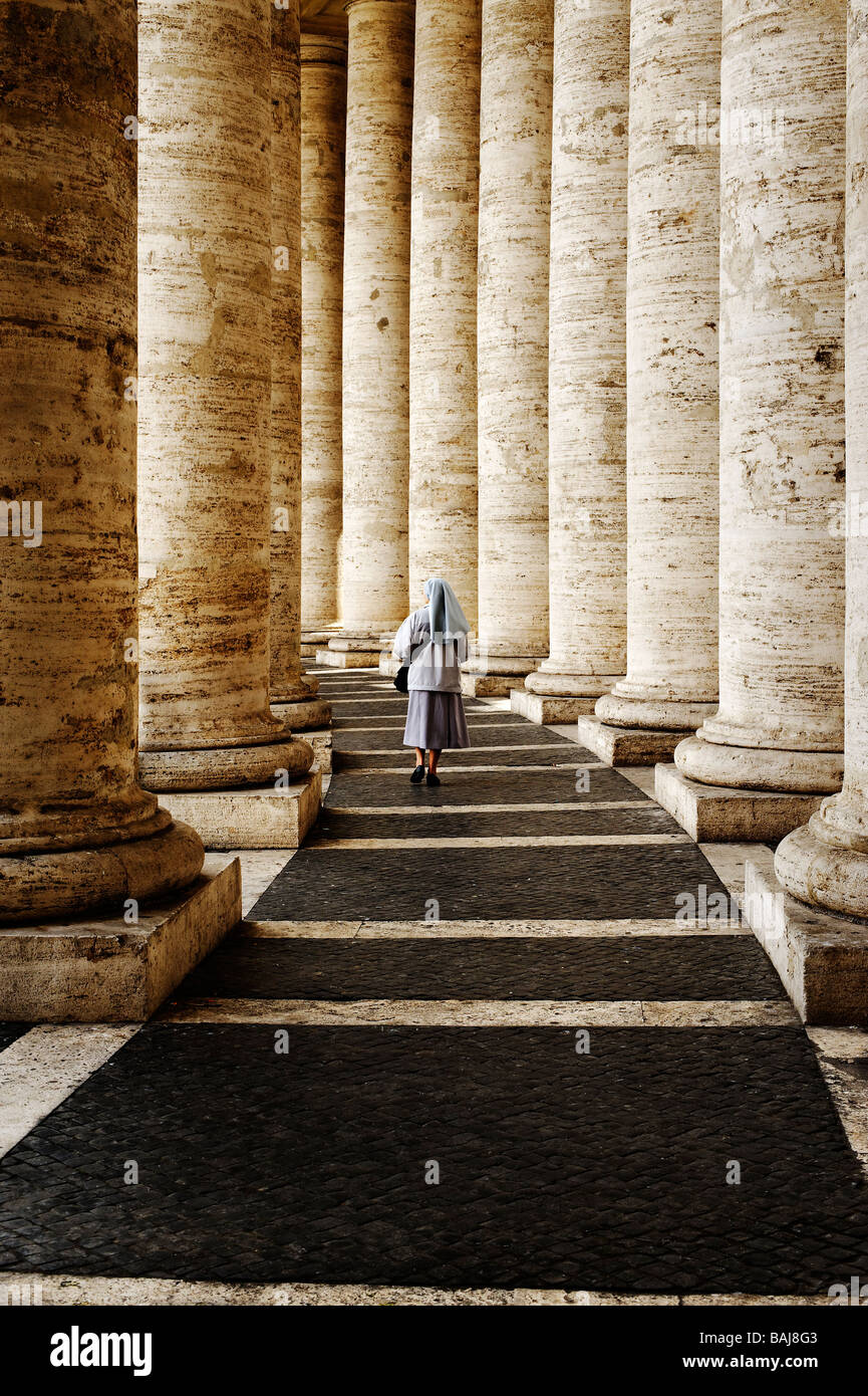 A nun walking within the Colonnade at Piazza San Pietro in the Vatican Stock Photo