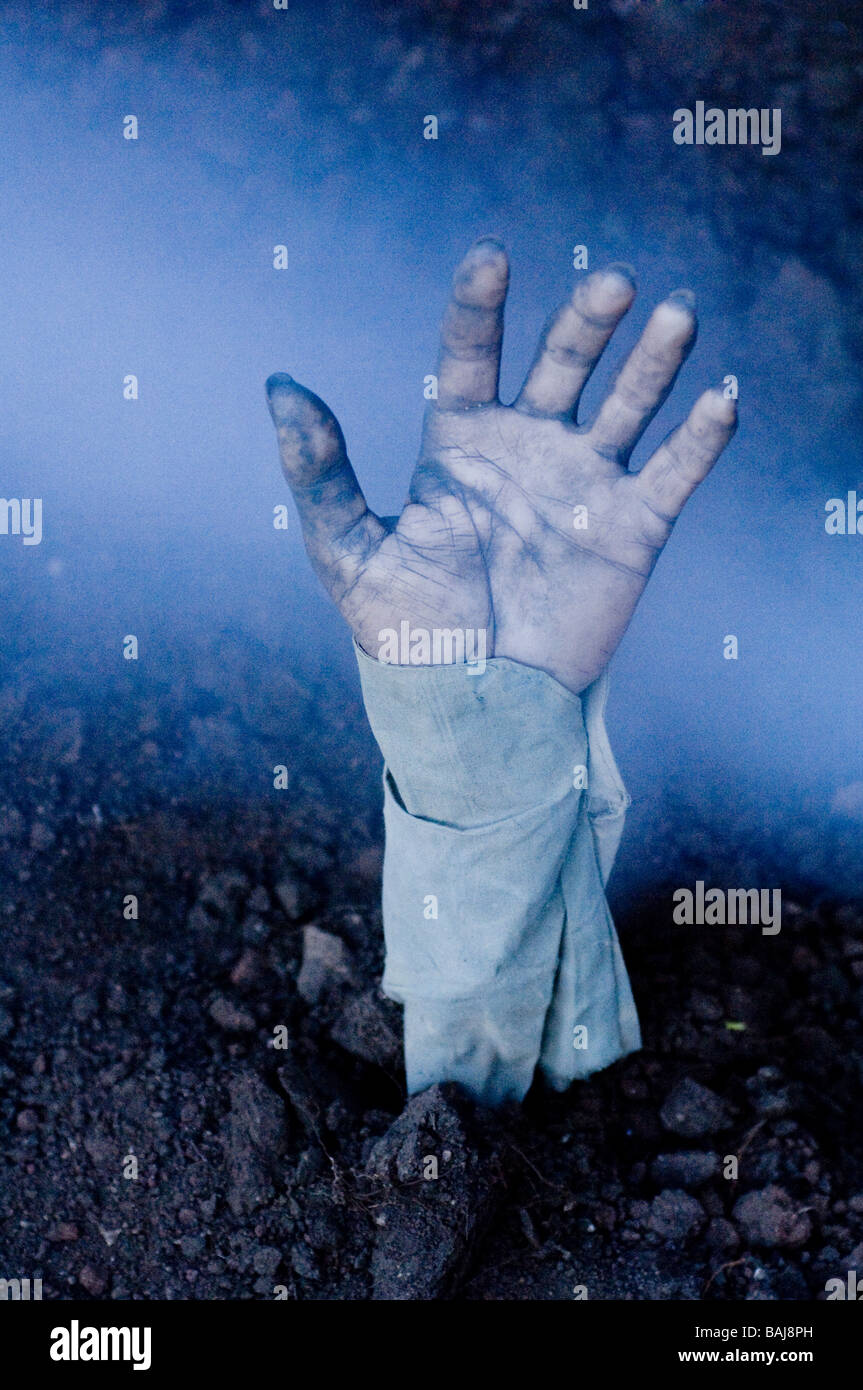 Zombie hand coming out of a fresh grave. Stock Photo