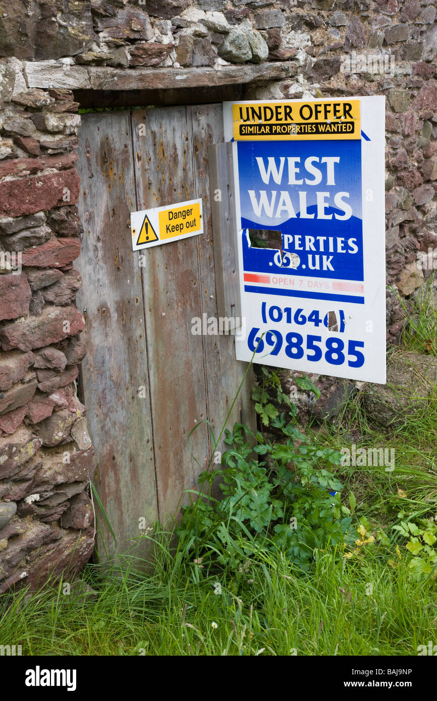 Estate agent s sign on a derelict cottage for sale Stock Photo